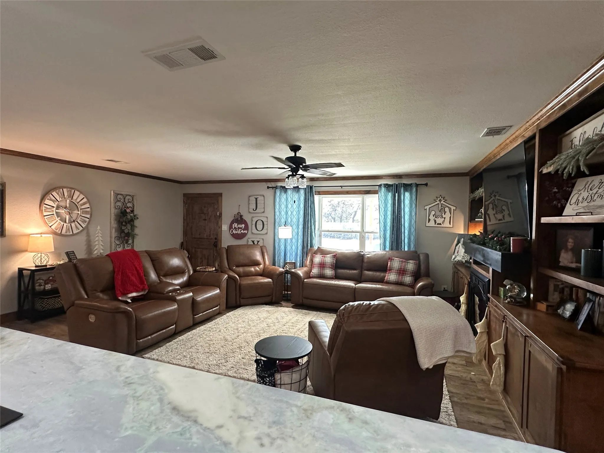 Living area featuring ornamental molding, ceiling fan, and wood finished floors