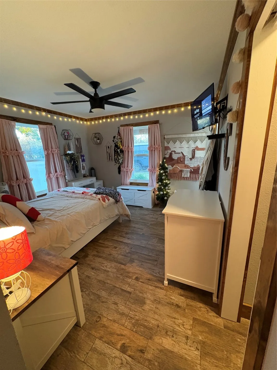 Bedroom with dark wood-style floors, multiple windows, and a ceiling fan