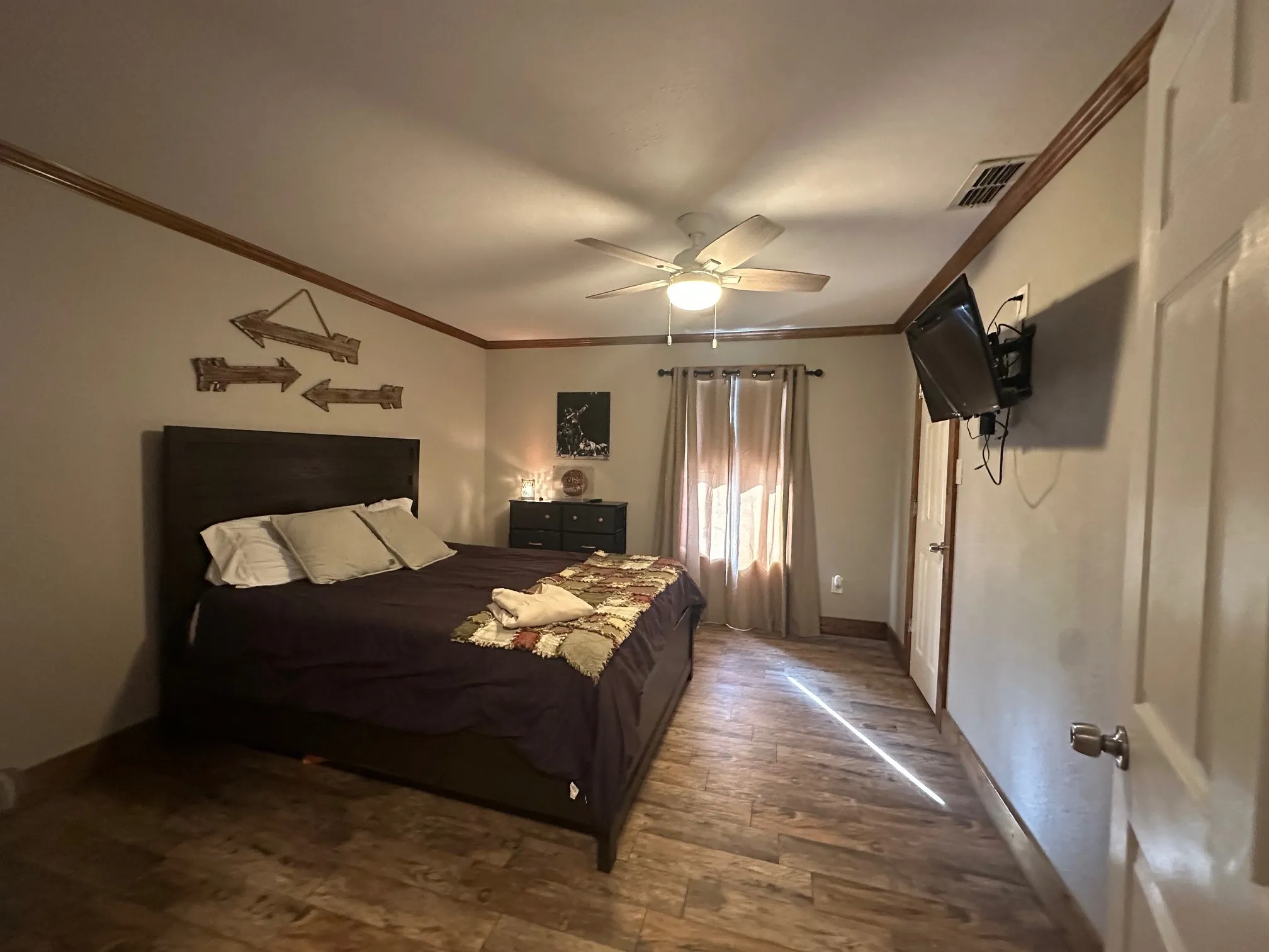 Bedroom with crown molding, wood finished floors, and a ceiling fan