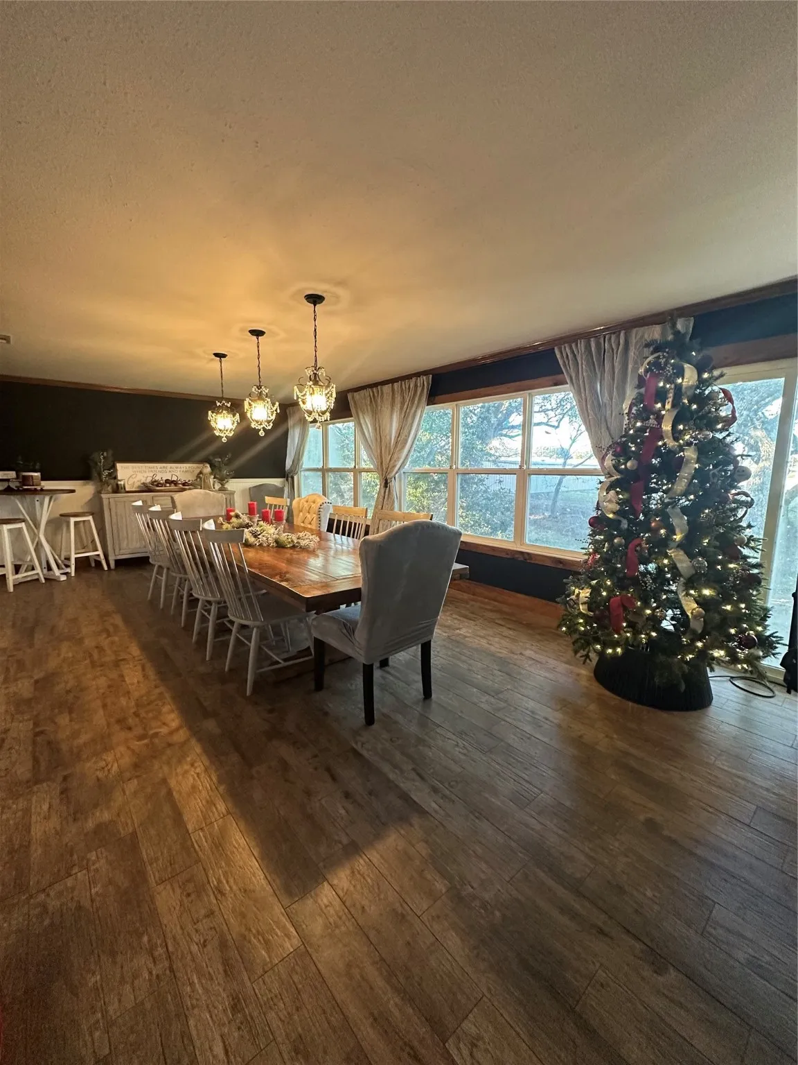 Dining room with a textured ceiling, dark wood-style floors, and a chandelier