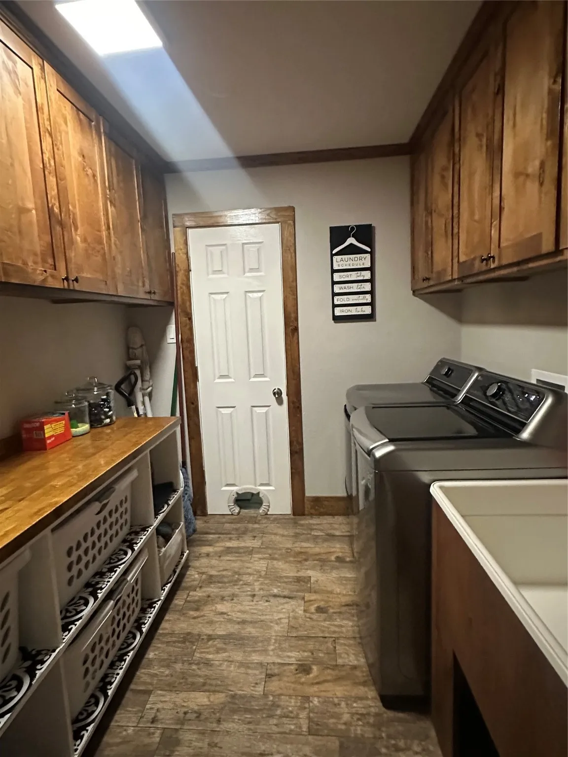 Laundry area with cabinet space, dark wood-style floors, washing machine and clothes dryer, and crown molding