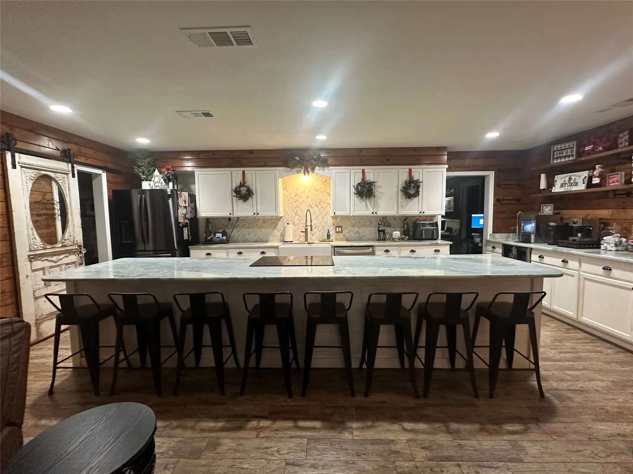 Kitchen with wooden walls, white cabinets, a spacious island, a barn door, and a kitchen breakfast bar