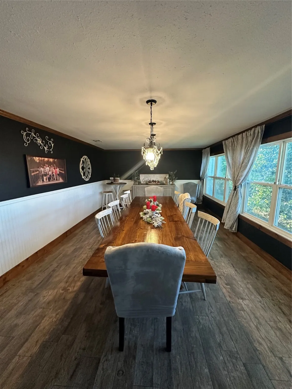 Dining area with a textured ceiling, wainscoting, a chandelier, and dark wood-style flooring