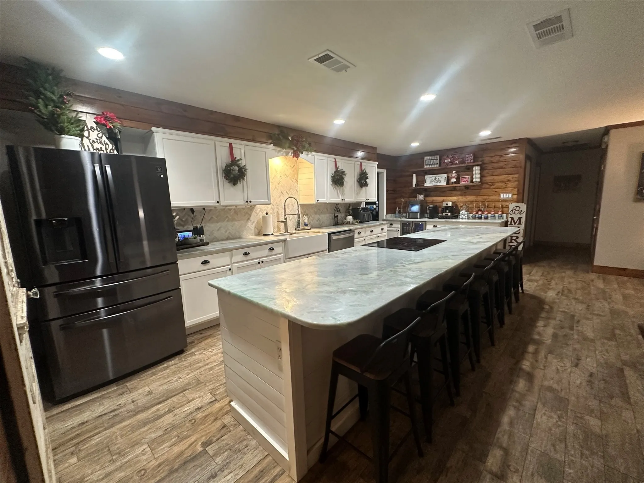 Kitchen featuring refrigerator with ice dispenser, white cabinetry, a large island, light wood-style floors, and recessed lighting