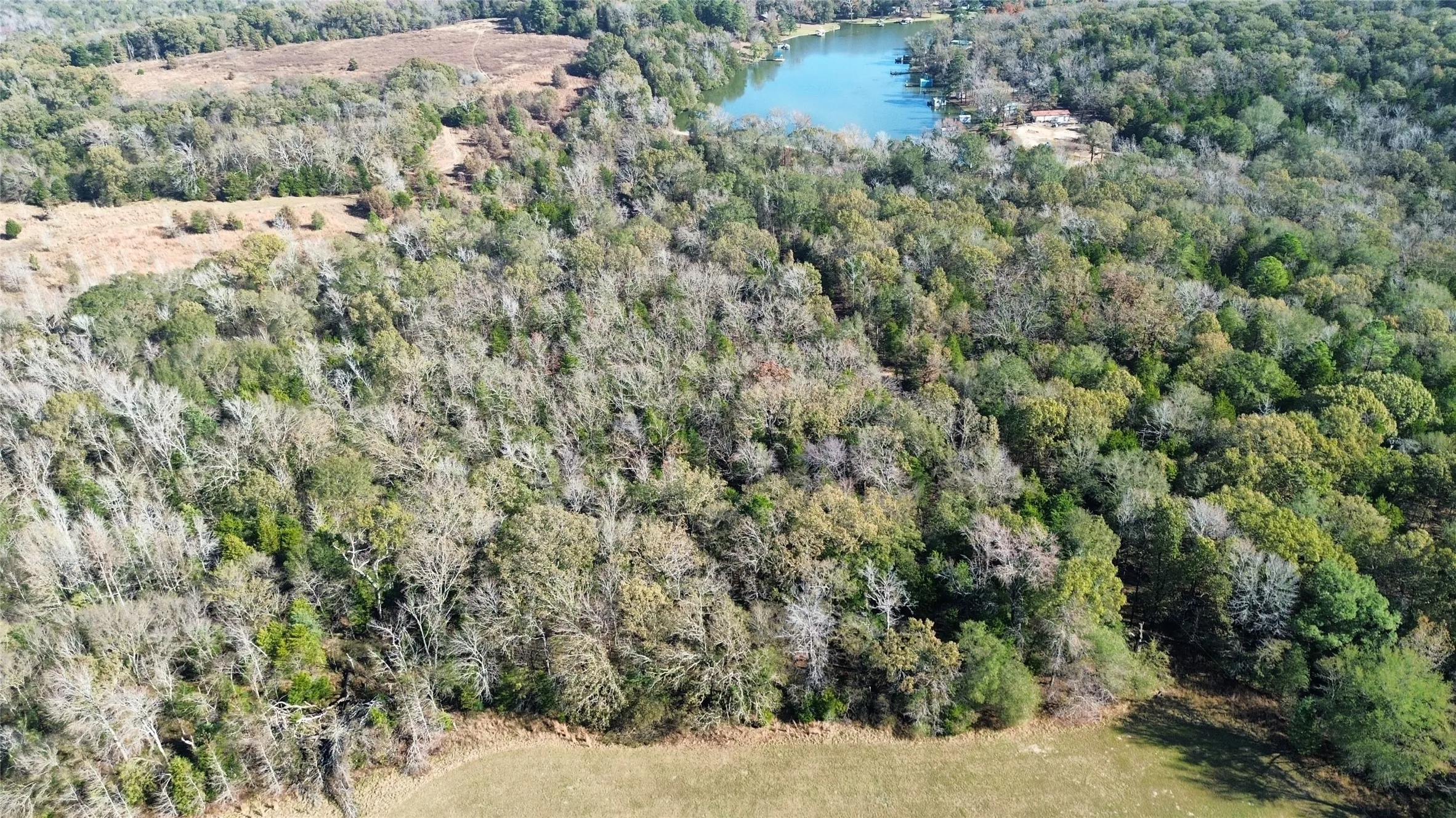 Aerial view of property and surrounding area featuring a large body of water and a heavily wooded area