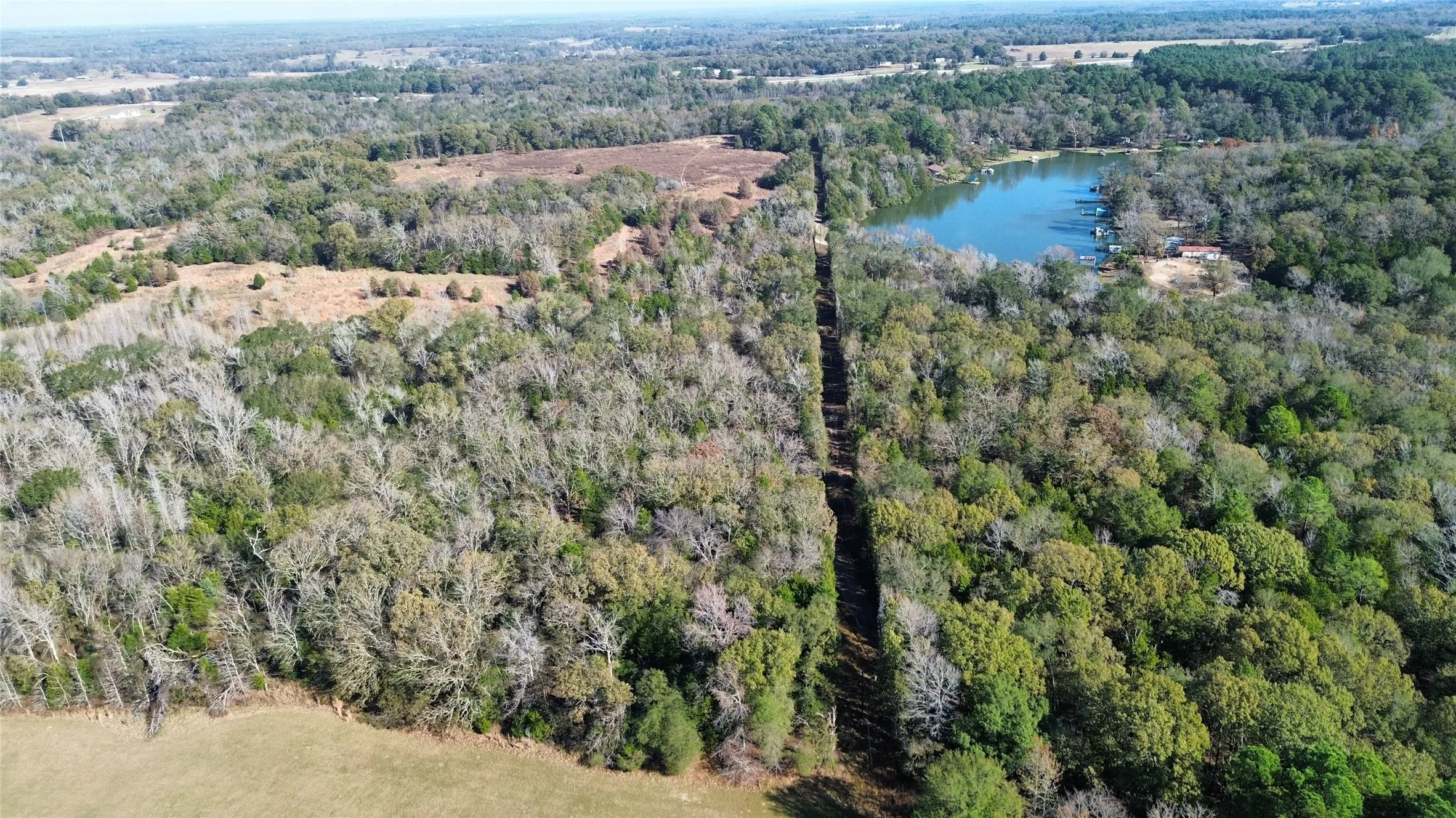 View of property location with a large body of water and a heavily wooded area