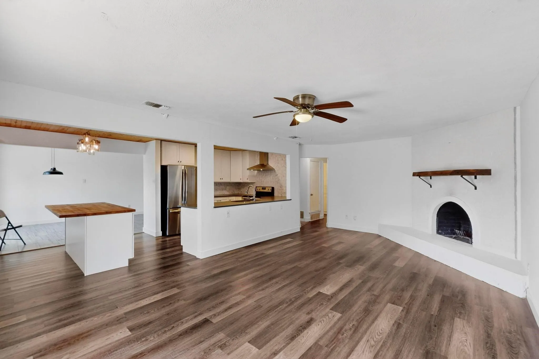 Unfurnished living room with a chandelier, ceiling fan, a fireplace, and dark wood-style flooring