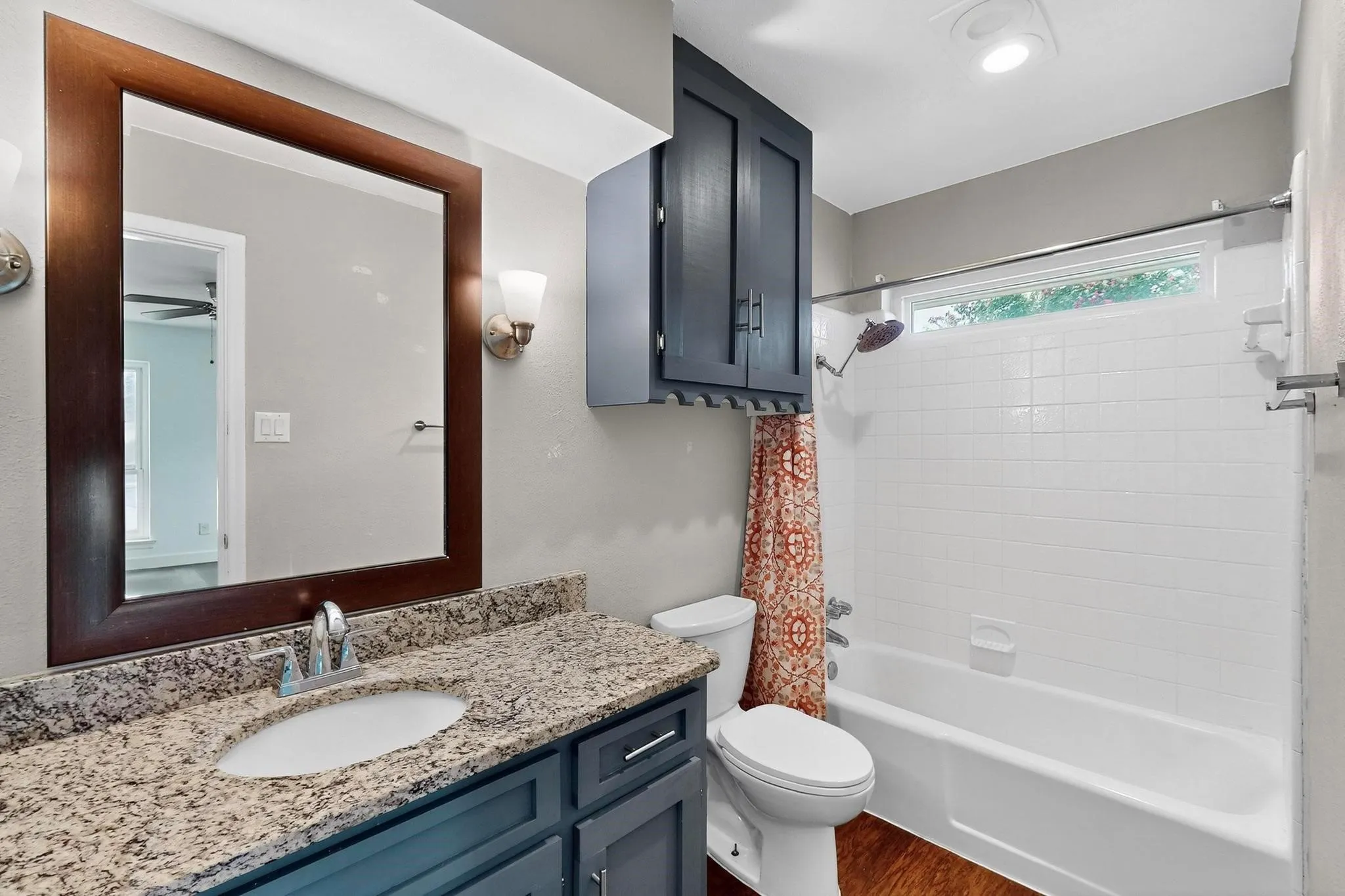 Bathroom with shower / bath combo with shower curtain, vanity, and dark wood-style flooring