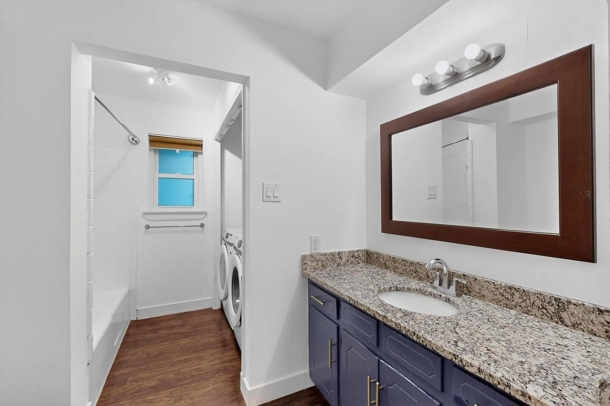 Bathroom featuring vanity, dark wood finished floors, bathing tub / shower combination, and separate washer and dryer