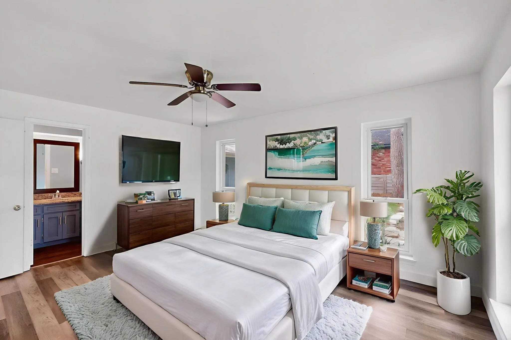 Bedroom with light wood finished floors, ceiling fan, and connected bathroom