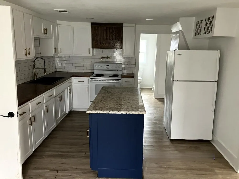 Kitchen featuring white appliances, white cabinetry, blue cabinetry, and backsplash