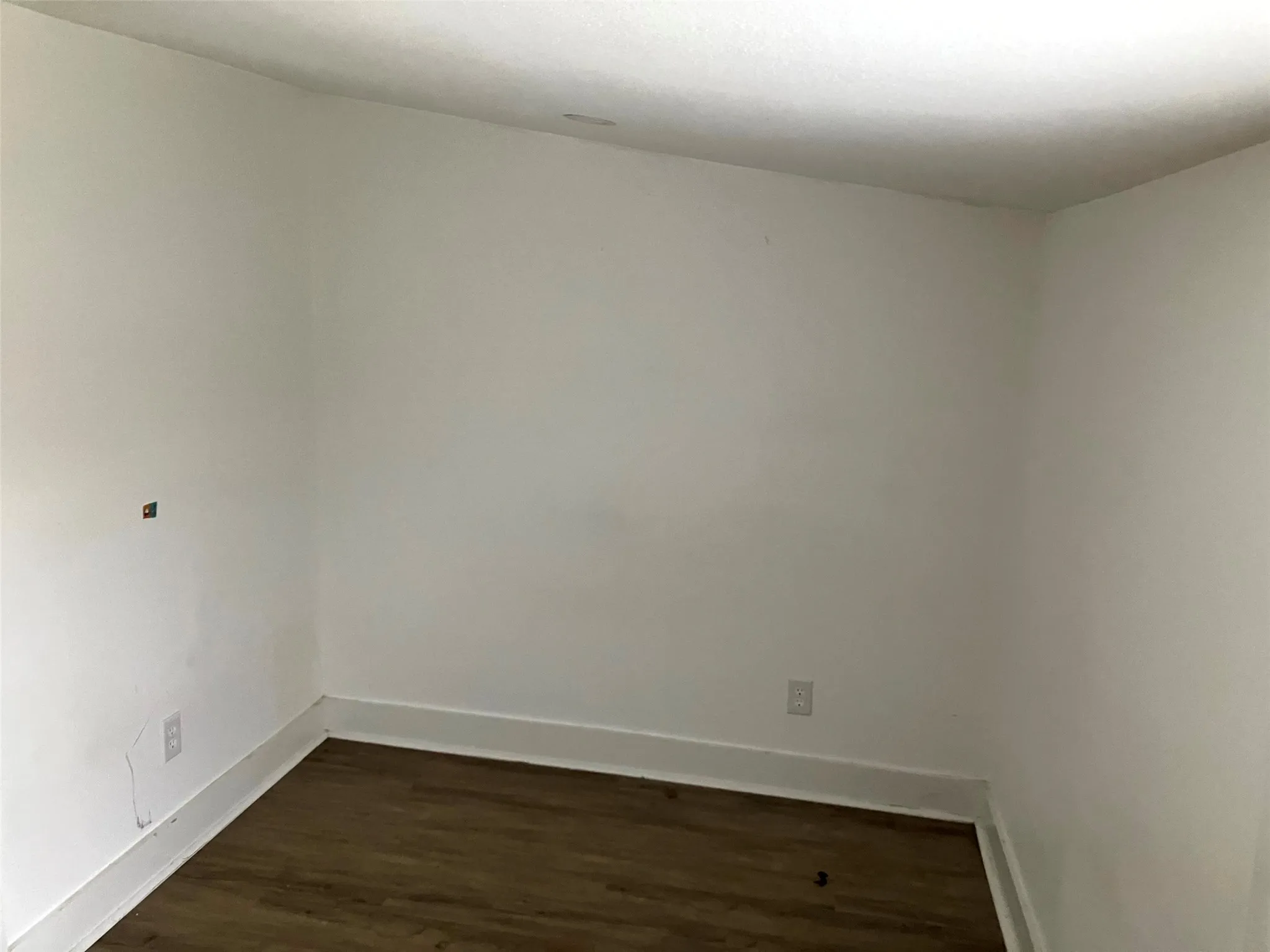 Empty room featuring dark wood-style floors and baseboards