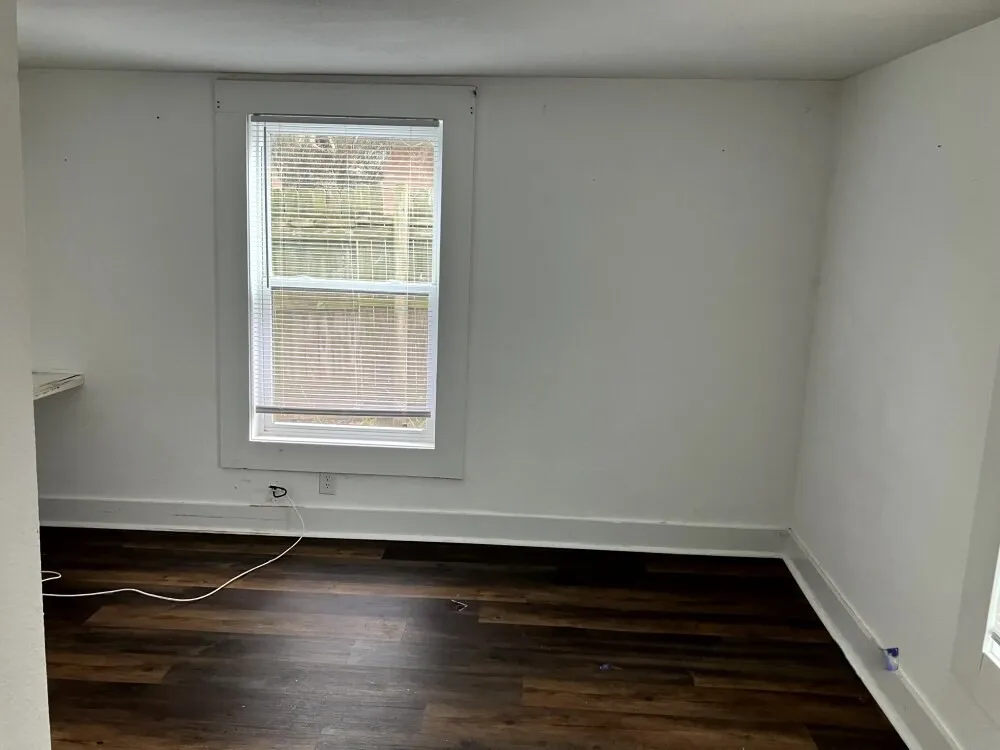 Empty room featuring baseboards and dark wood-type flooring