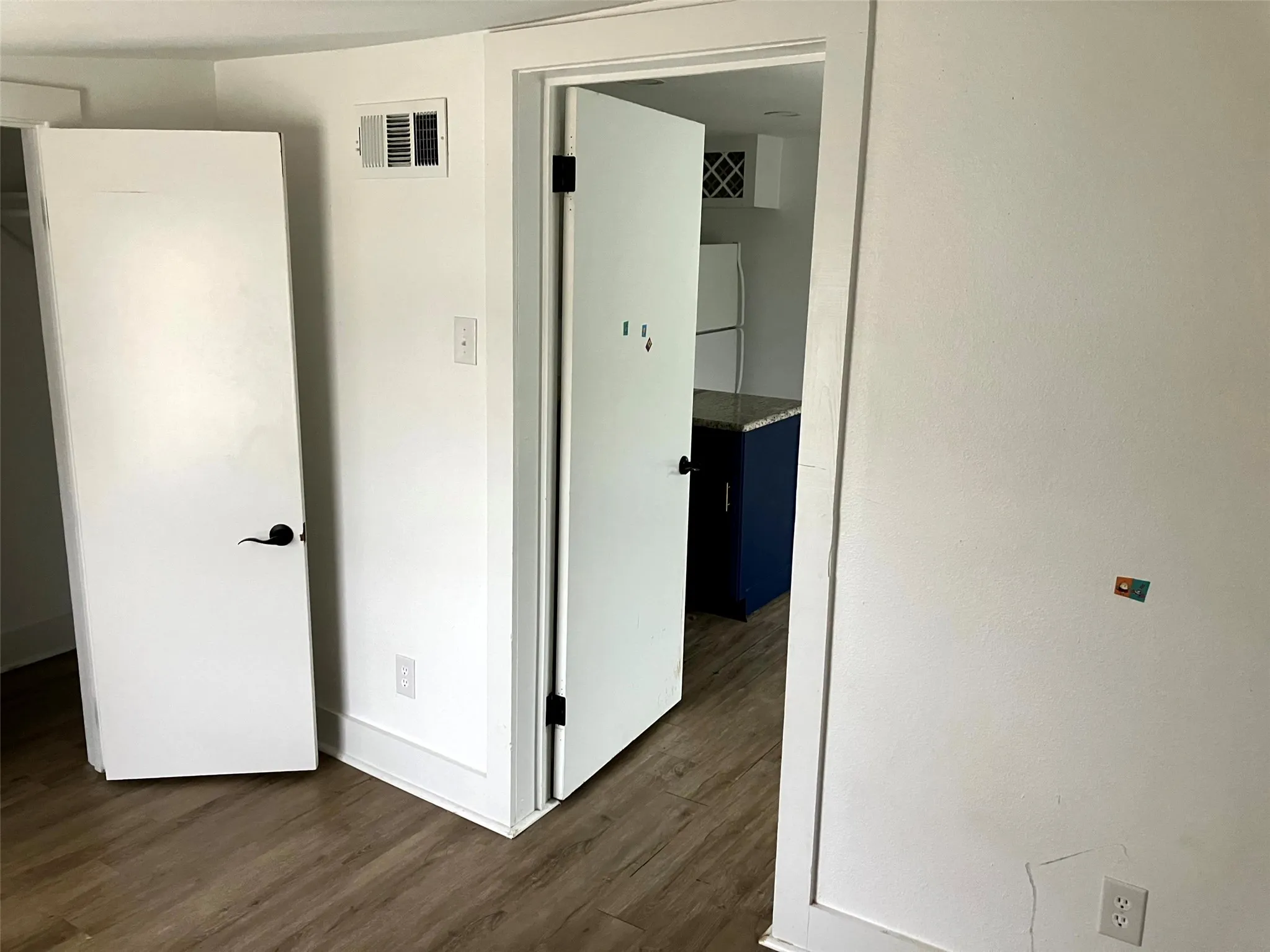 Unfurnished bedroom with dark wood-type flooring and freestanding refrigerator
