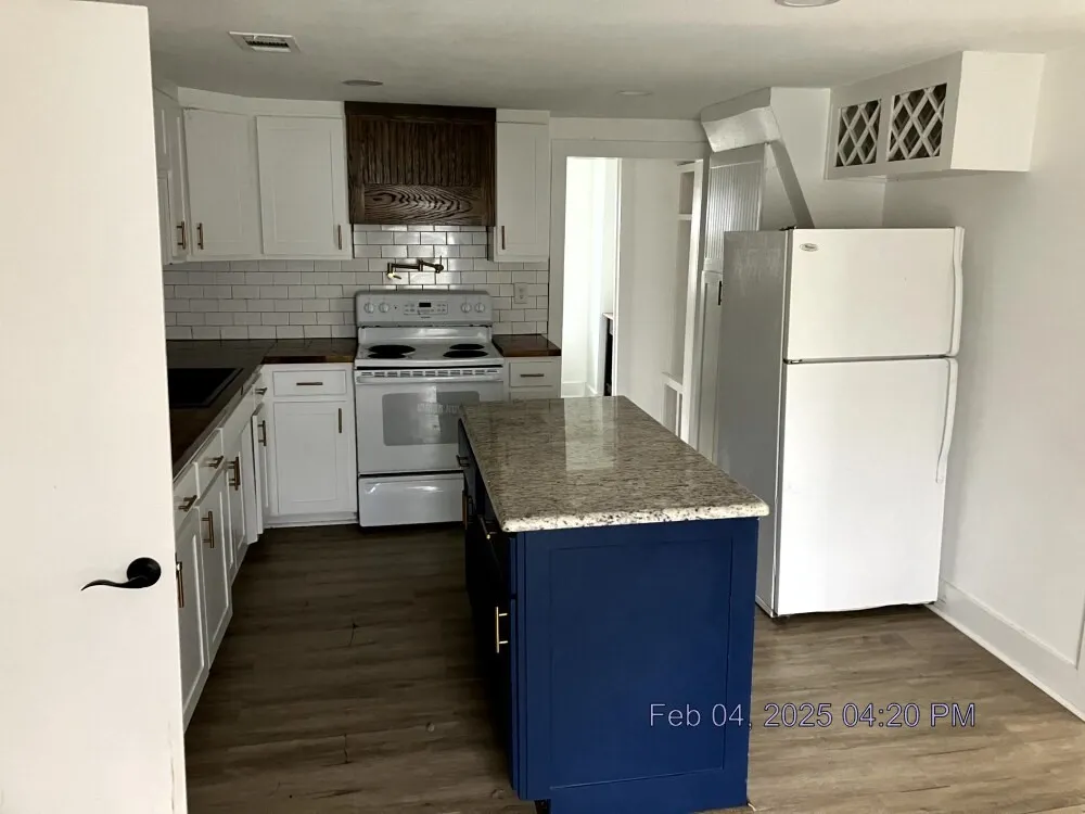 Kitchen featuring white appliances, white cabinets, blue cabinets, dark wood-style floors, and decorative backsplash