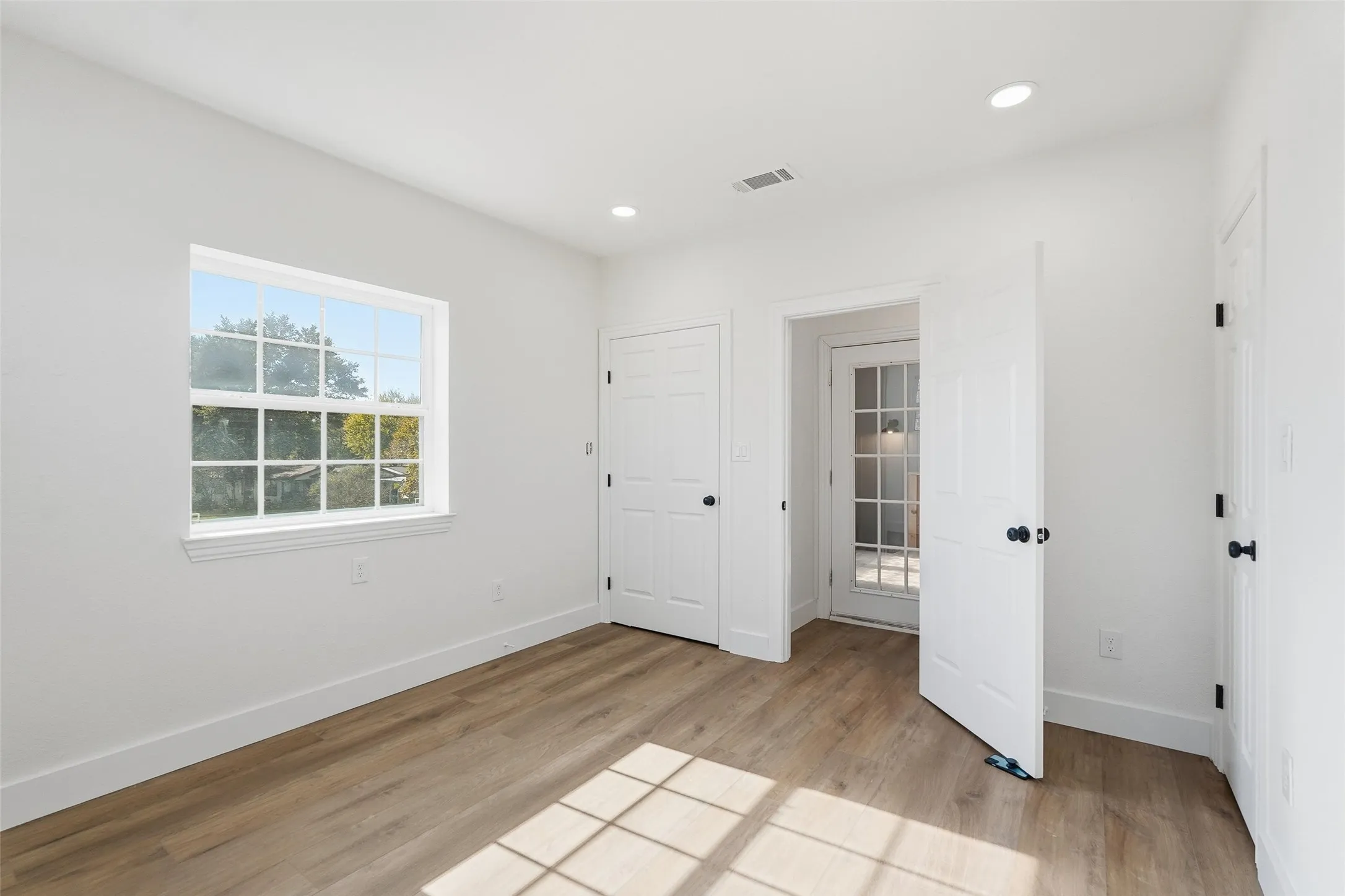 Upstairs bedroom with light wood-style floors and recessed lighting