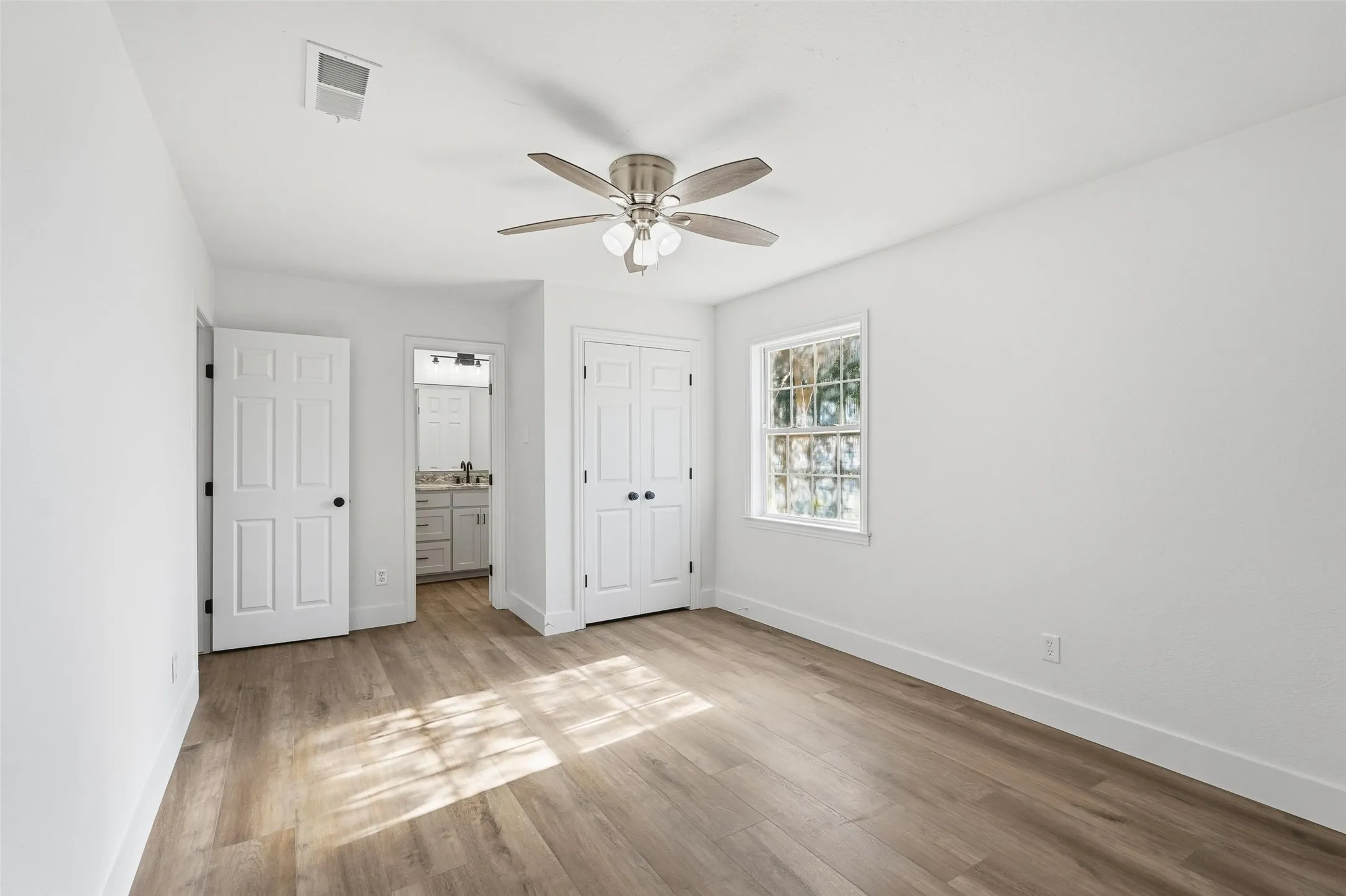 2nd primary with light wood-style flooring, ensuite, a closet, and a ceiling fan