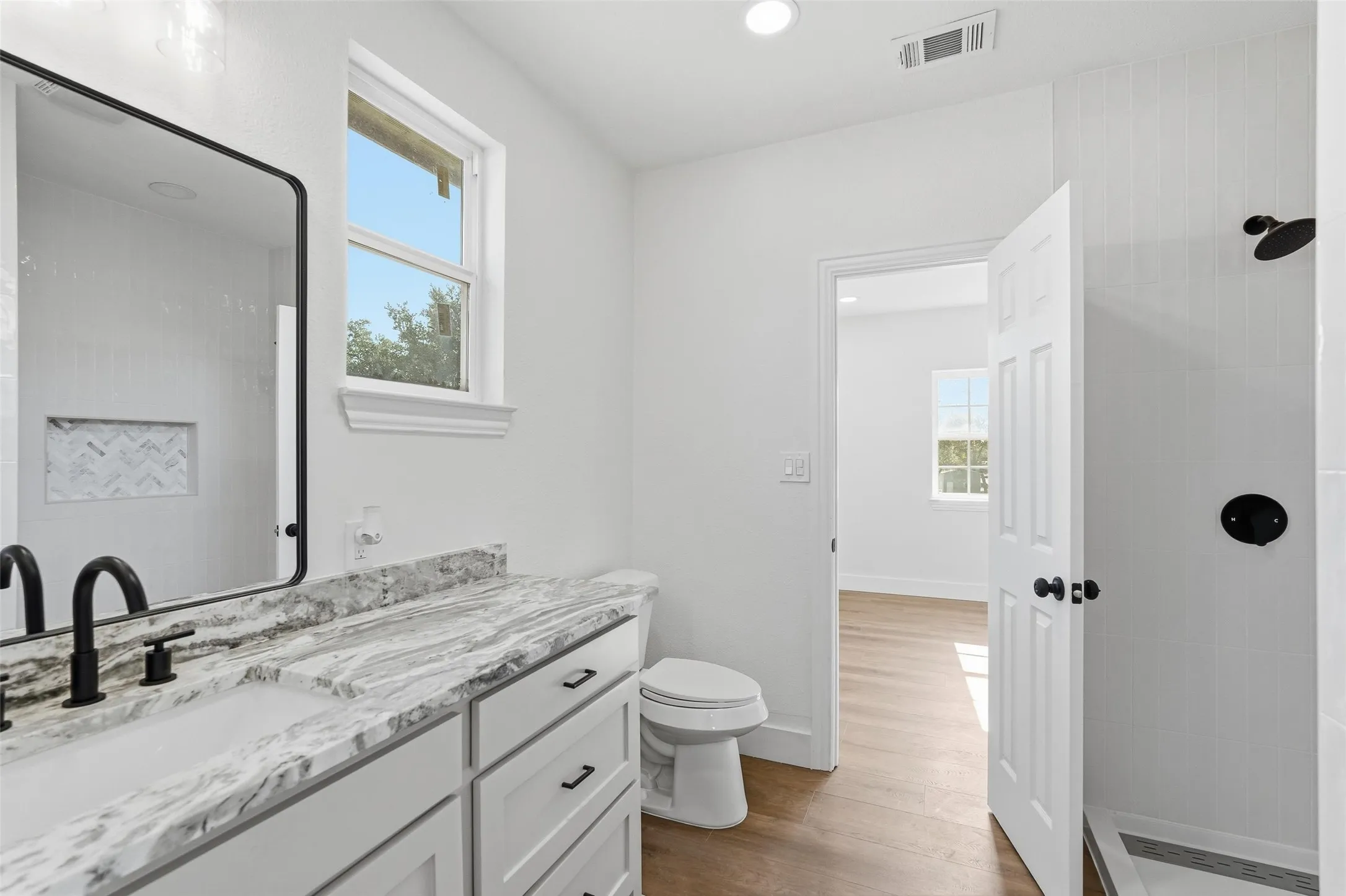 Upstairs bathroom featuring healthy amount of natural light, vanity, light wood finished floors, walk in shower, and recessed lighting