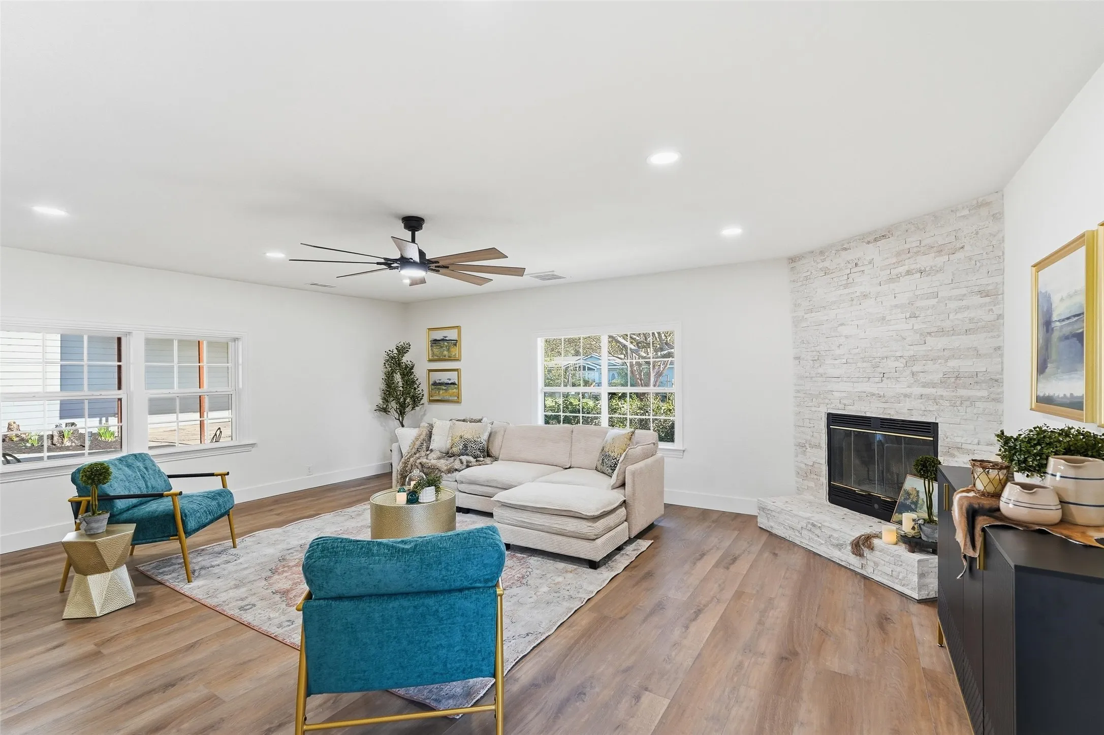 Living room featuring a ceiling fan, a fireplace, light wood-type flooring, and recessed lighting