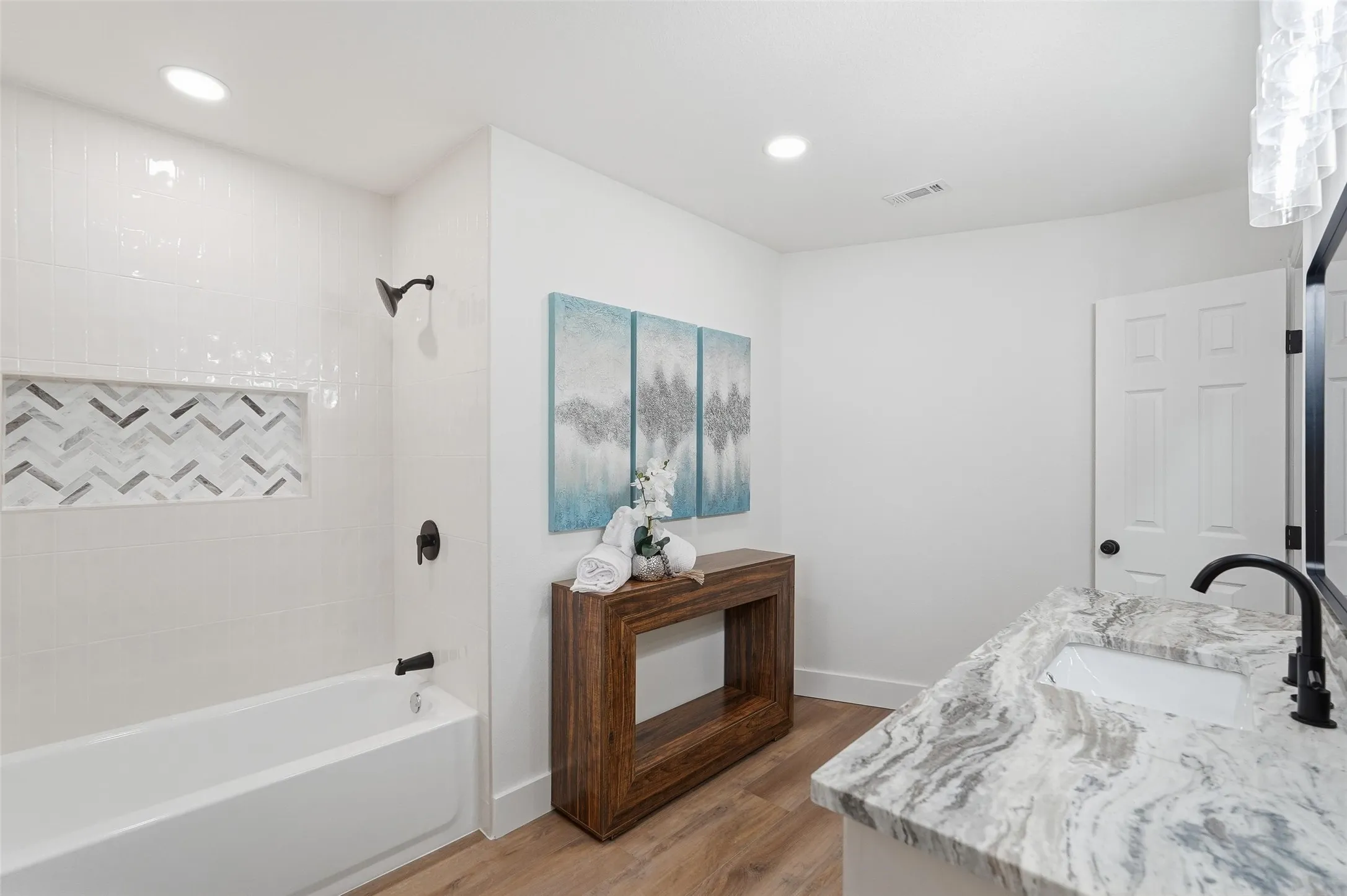 Full bathroom with vanity, tub / shower combination, light wood finished floors, and recessed lighting