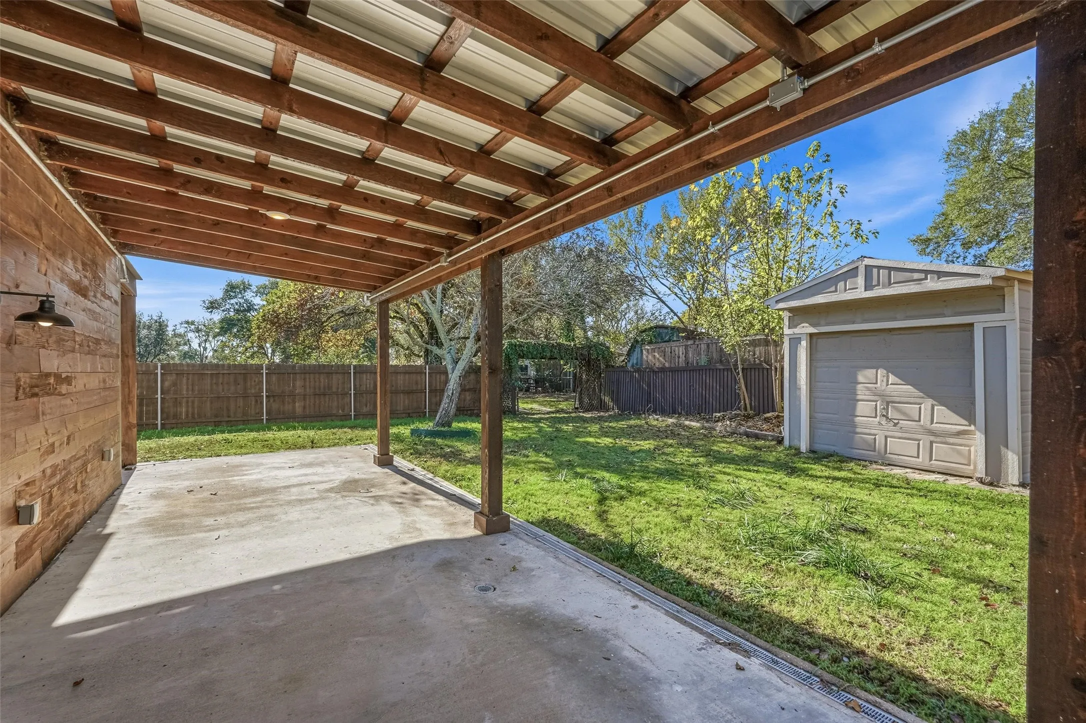 Fenced backyard featuring a patio area and an outdoor structure