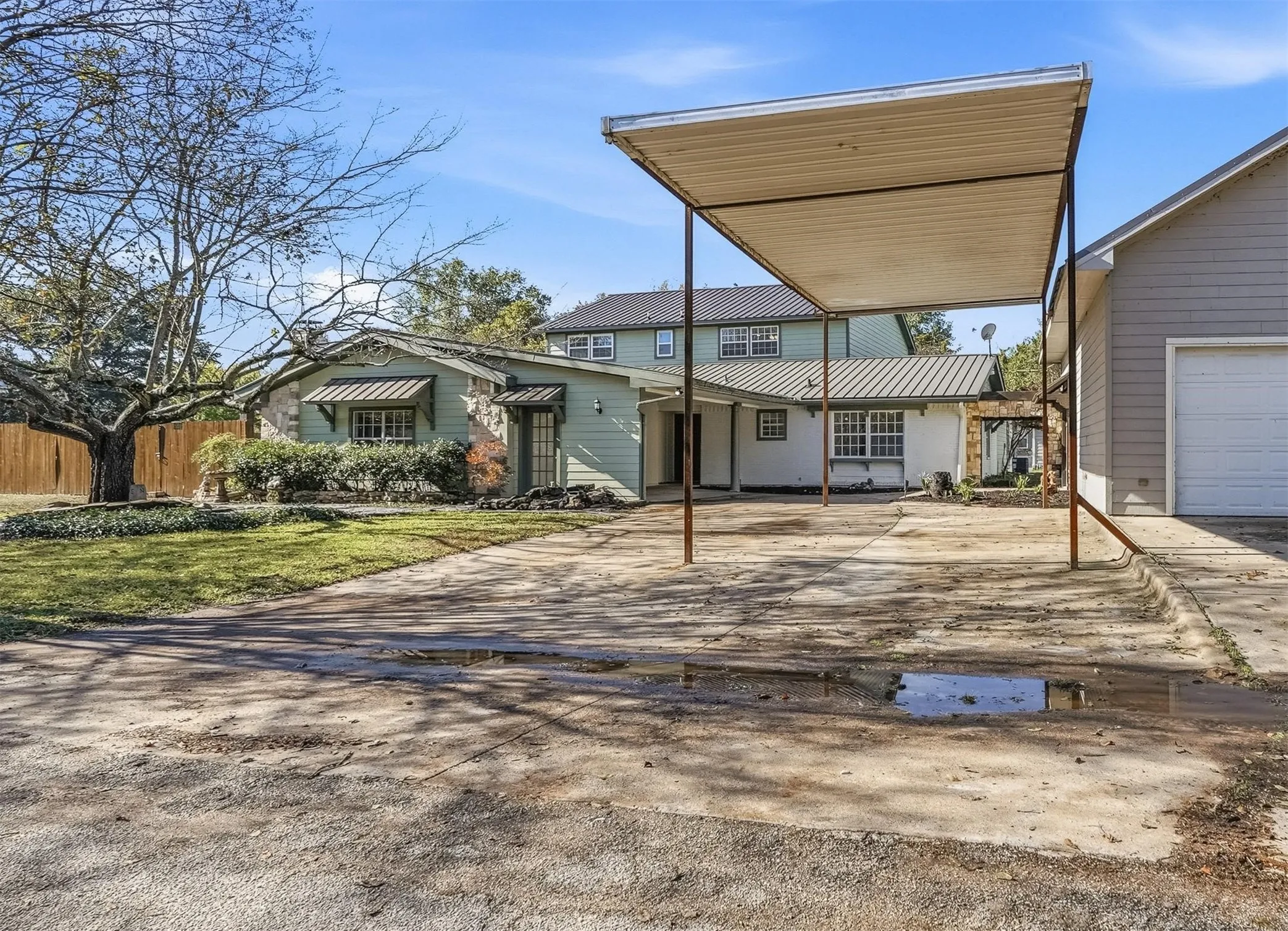 View of front of home with concrete driveway, a carport, and a metal roof
