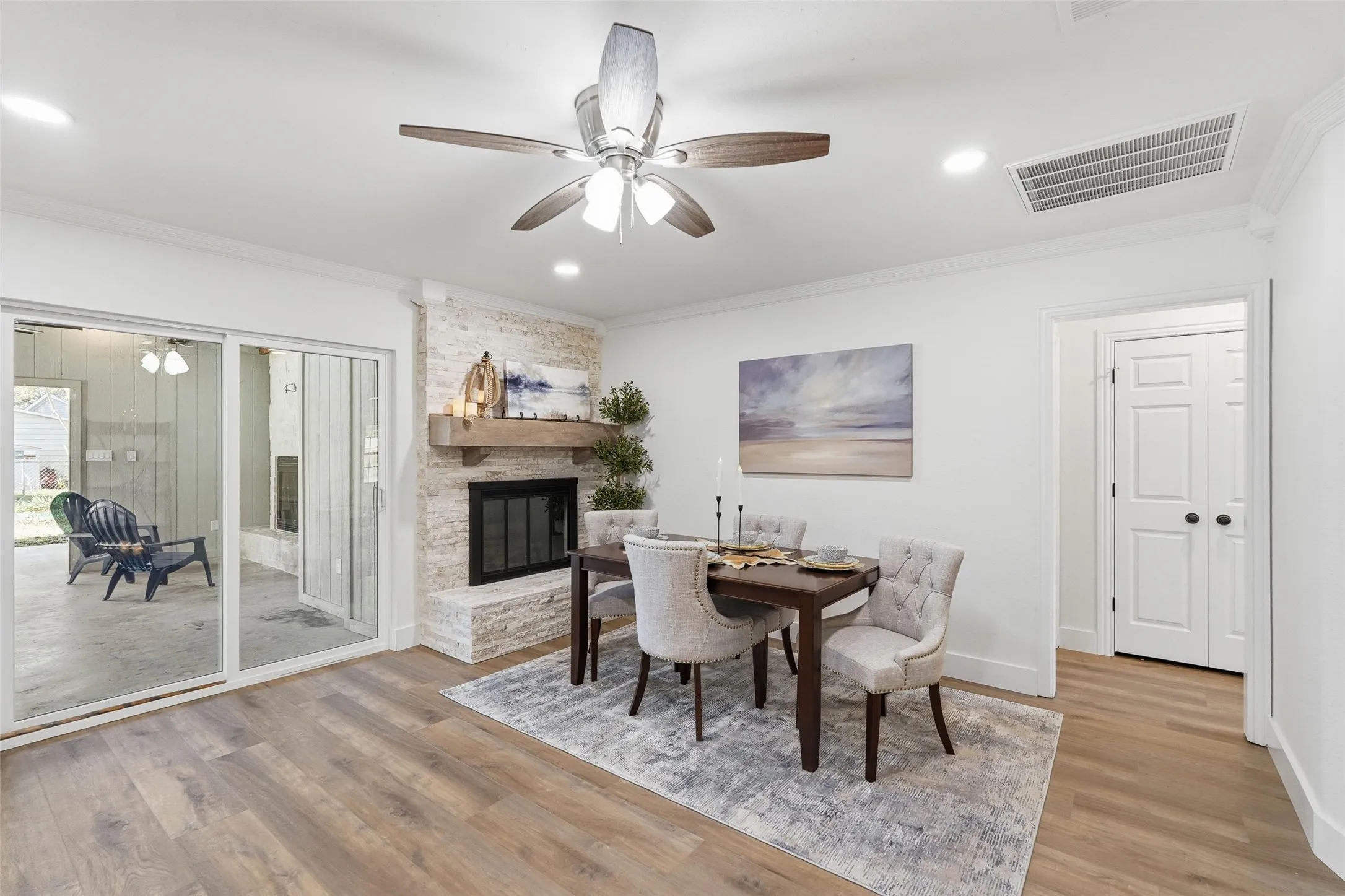 Dining area featuring ceiling fan, light wood-style floors, a fireplace, crown molding, and recessed lighting