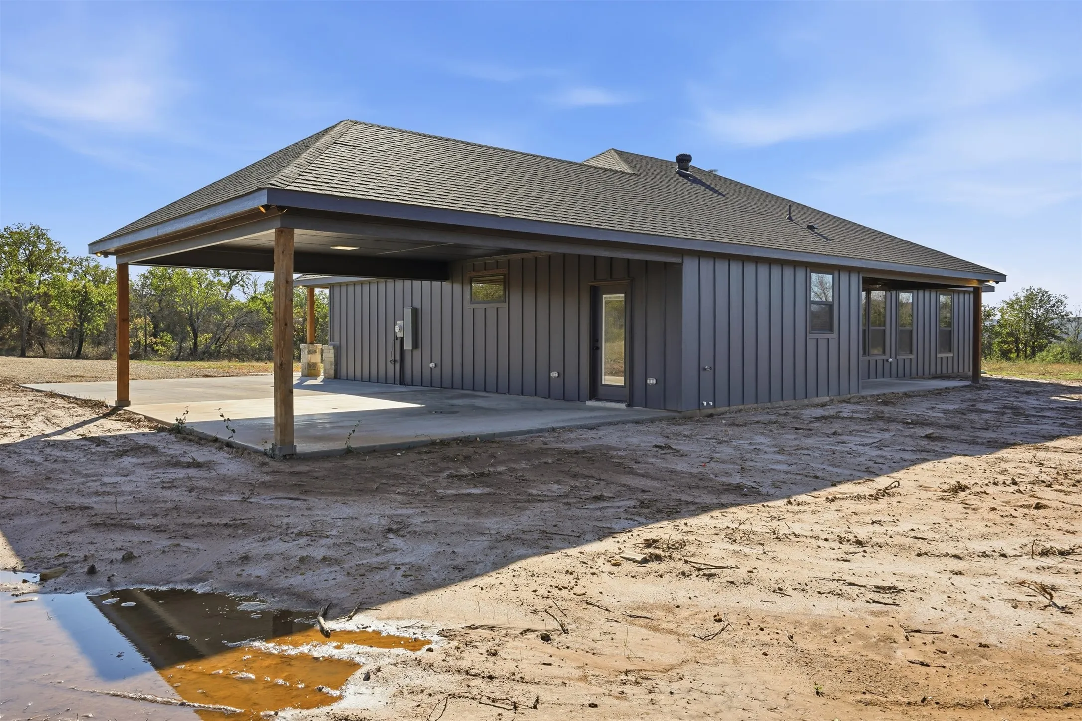 Rear view of house with roof with shingles, board and batten siding, and a patio area
