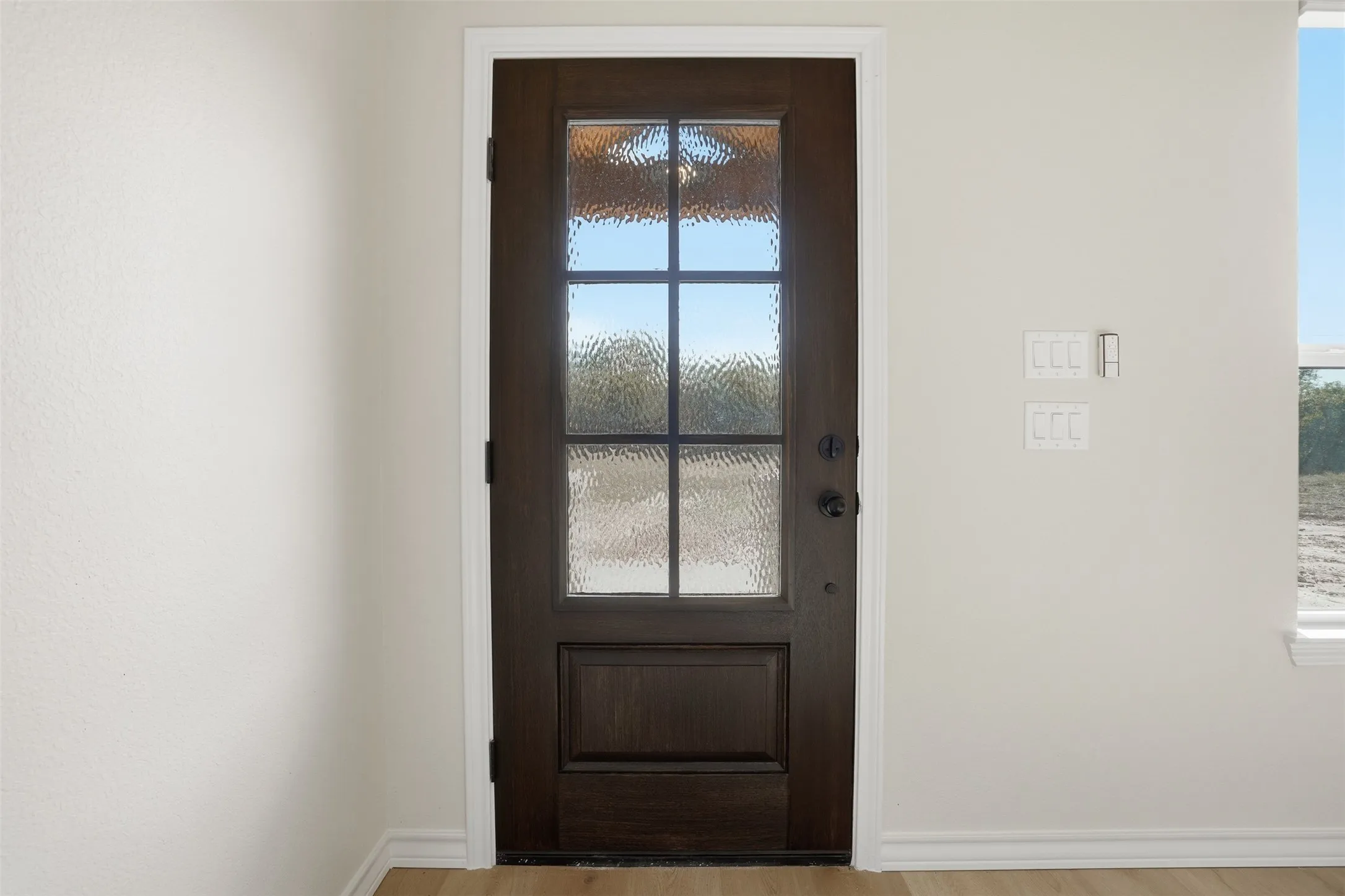 Doorway to outside with wood finished floors and baseboards
