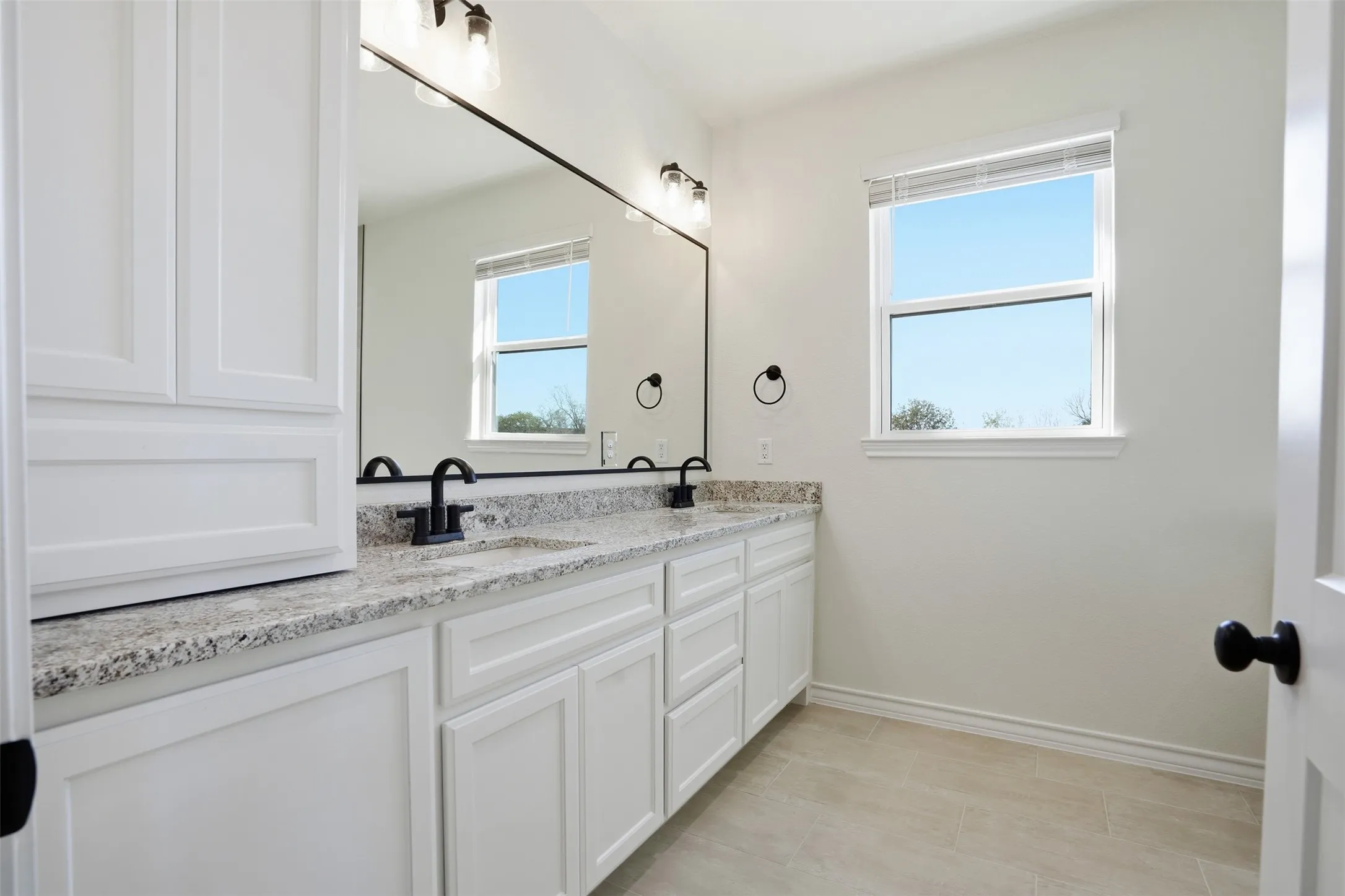 Bathroom with double vanity and baseboards