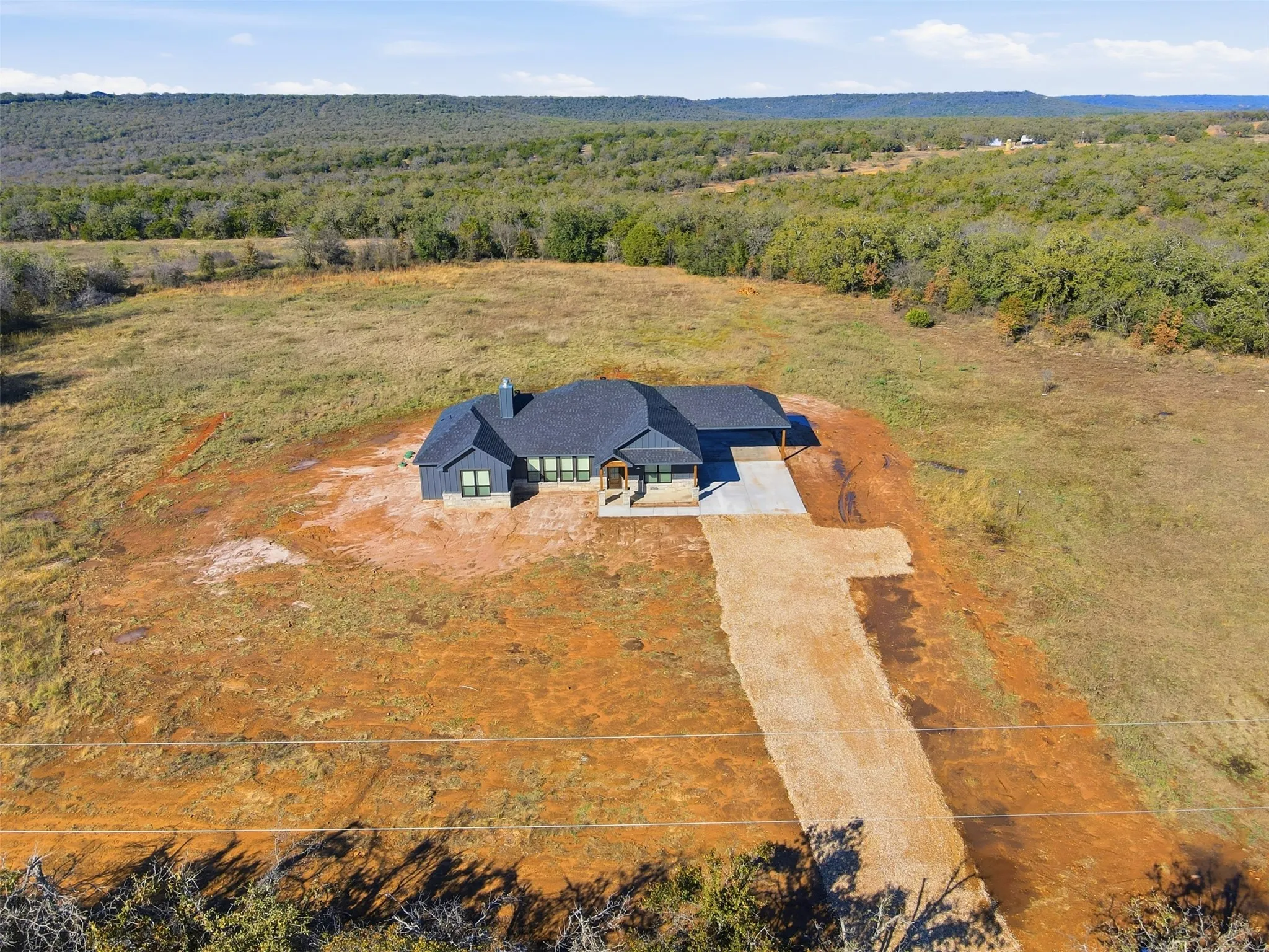Aerial view of property and surrounding area with a forest