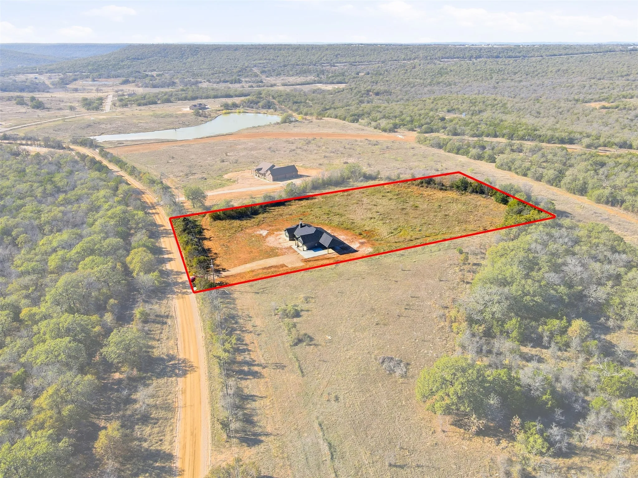 Aerial view of sparsely populated area with property parcel outlined and a nearby body of water