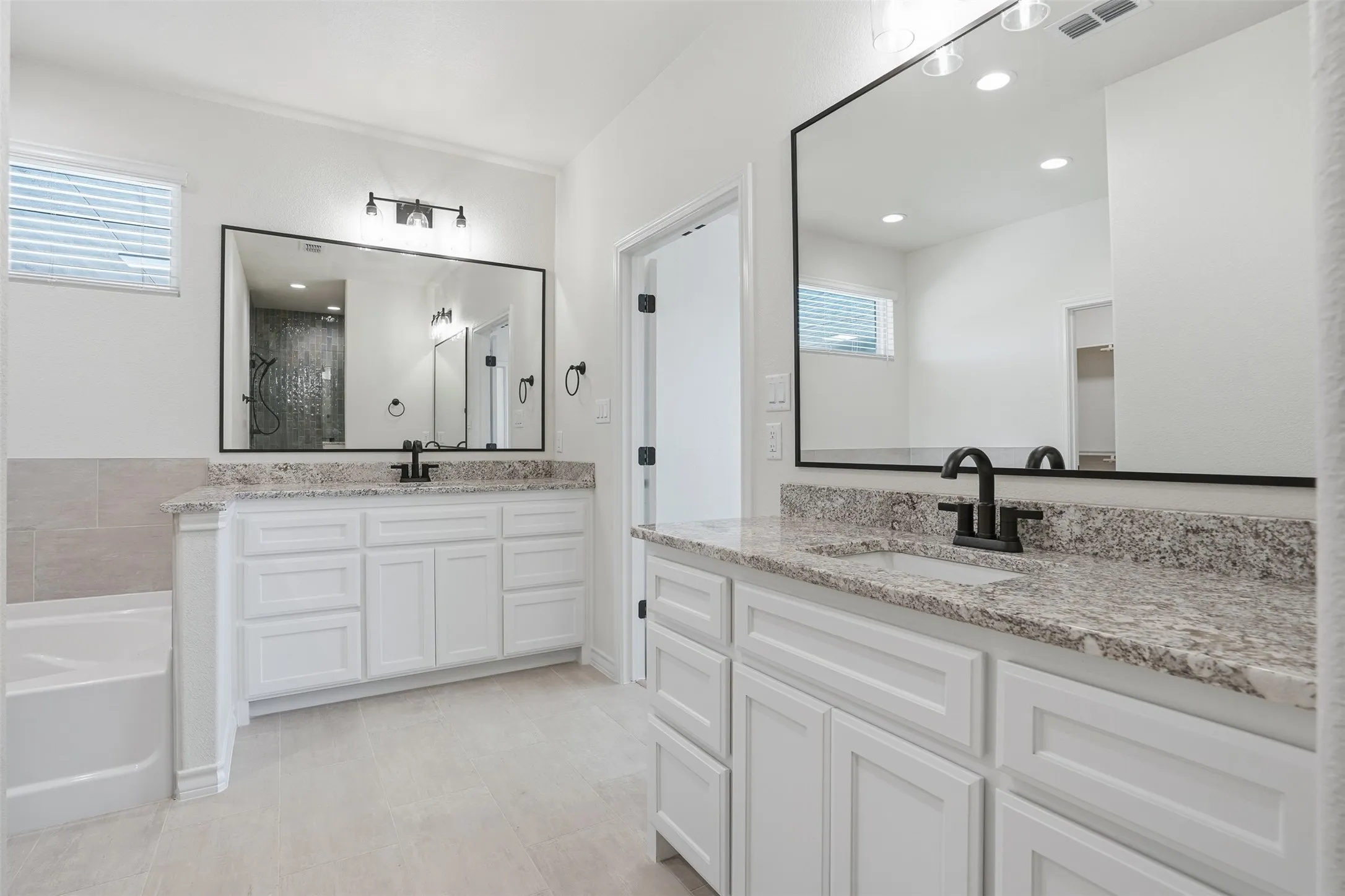 Bathroom featuring two vanities, healthy amount of natural light, a garden tub, and a shower stall