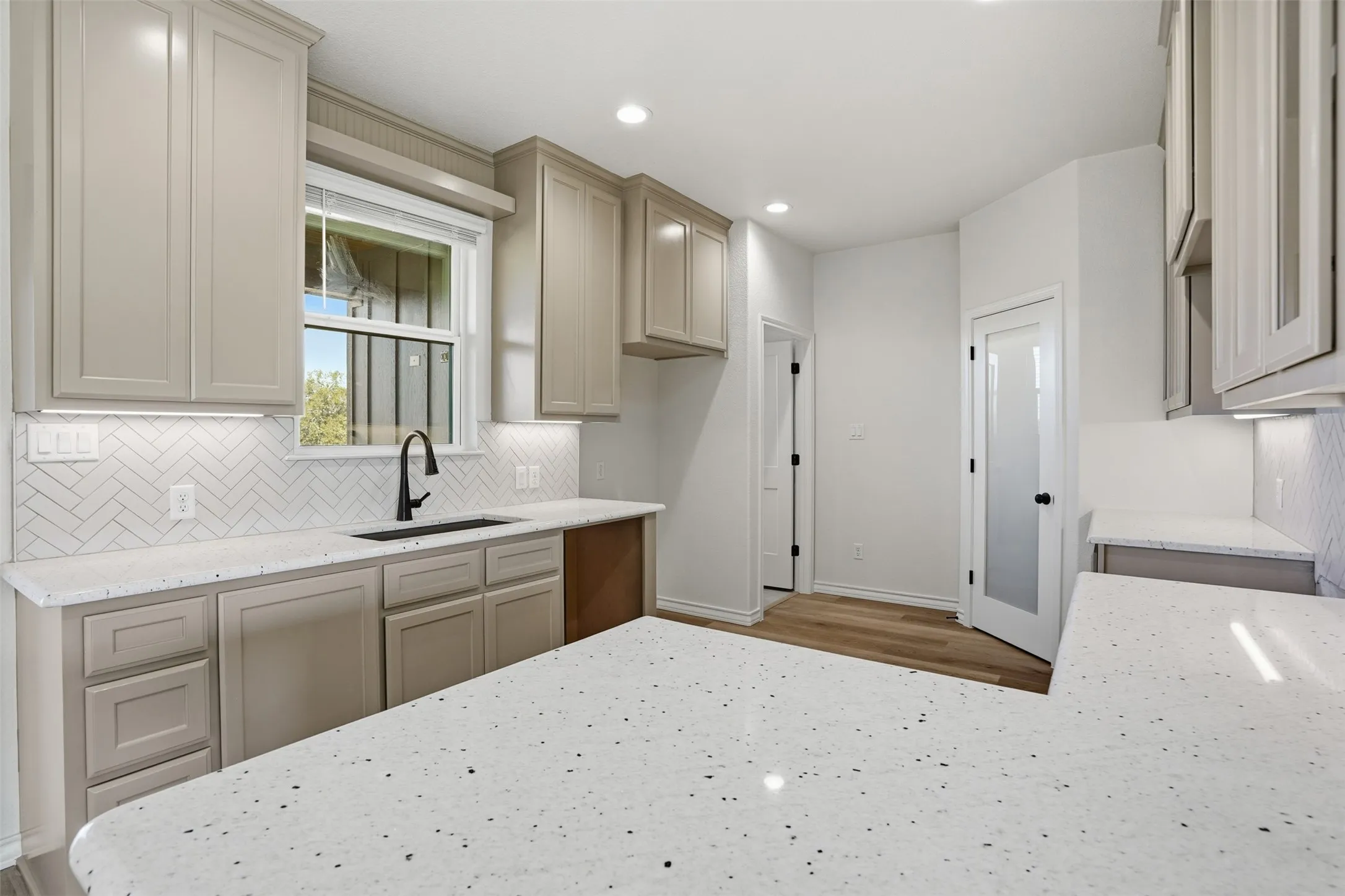 Kitchen with light stone countertops, decorative backsplash, and recessed lighting