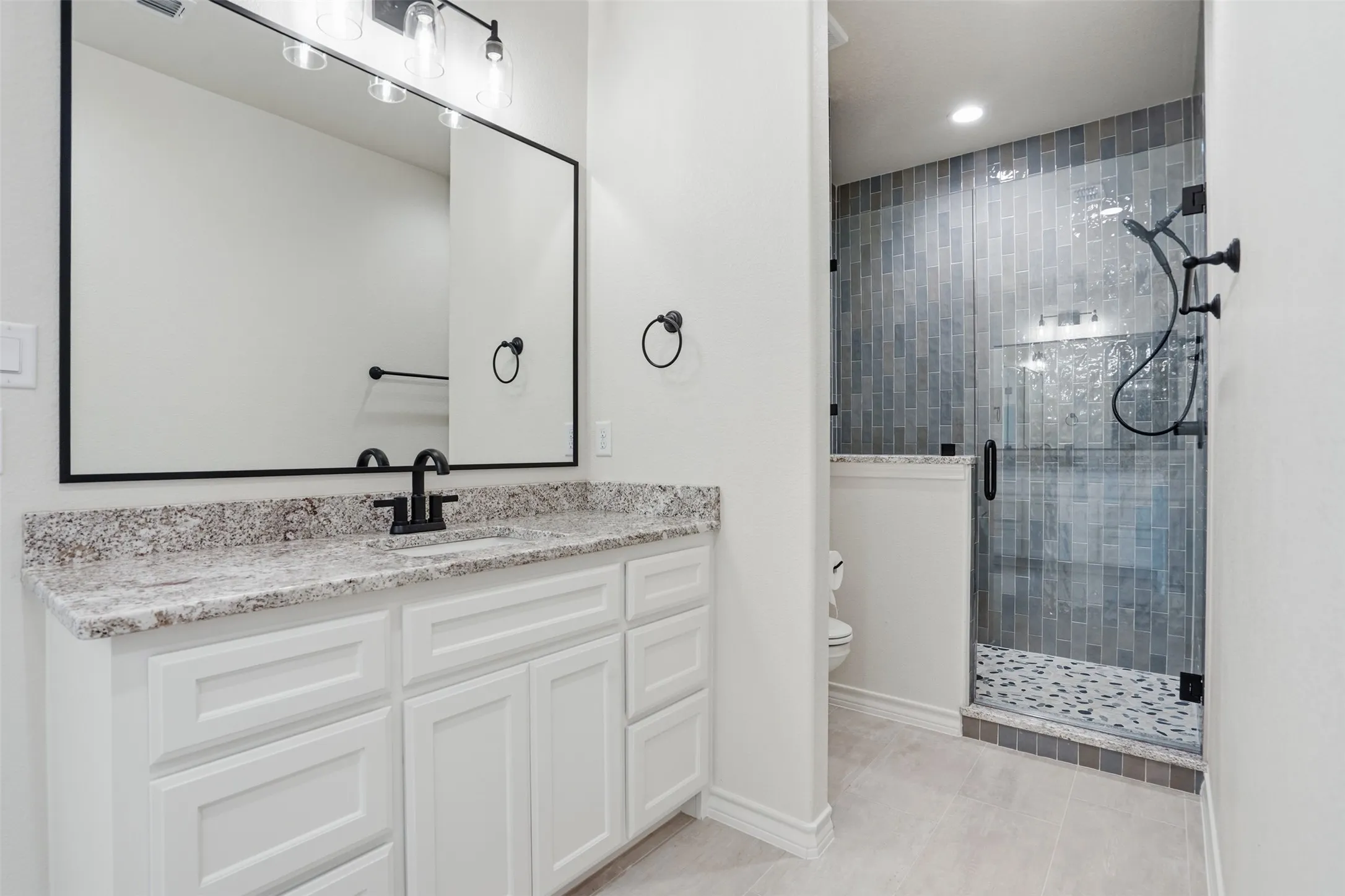 Bathroom featuring a shower stall, vanity, and light tile patterned floors