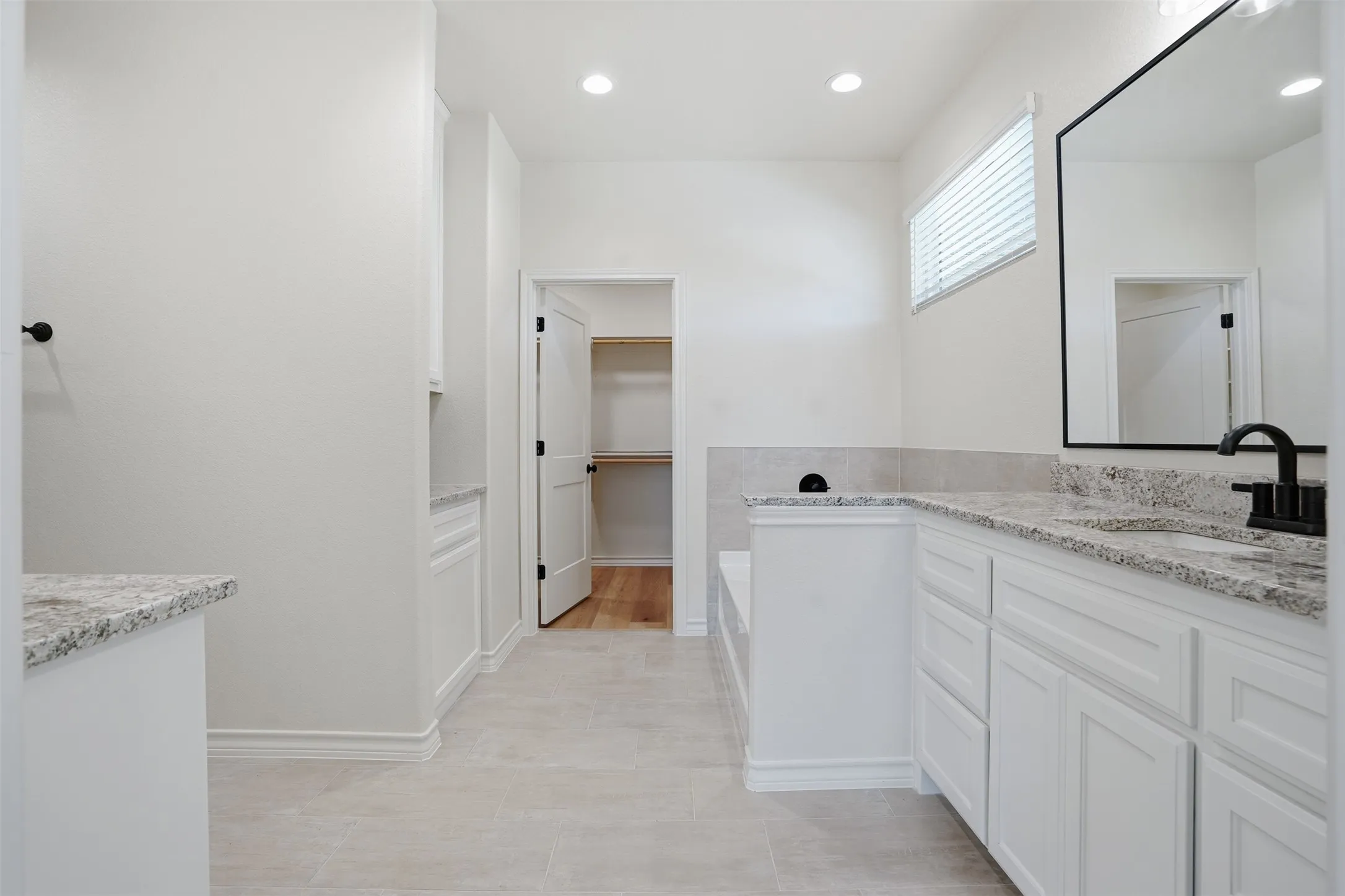 Full bathroom featuring vanity, a spacious closet, recessed lighting, and a tub to relax in