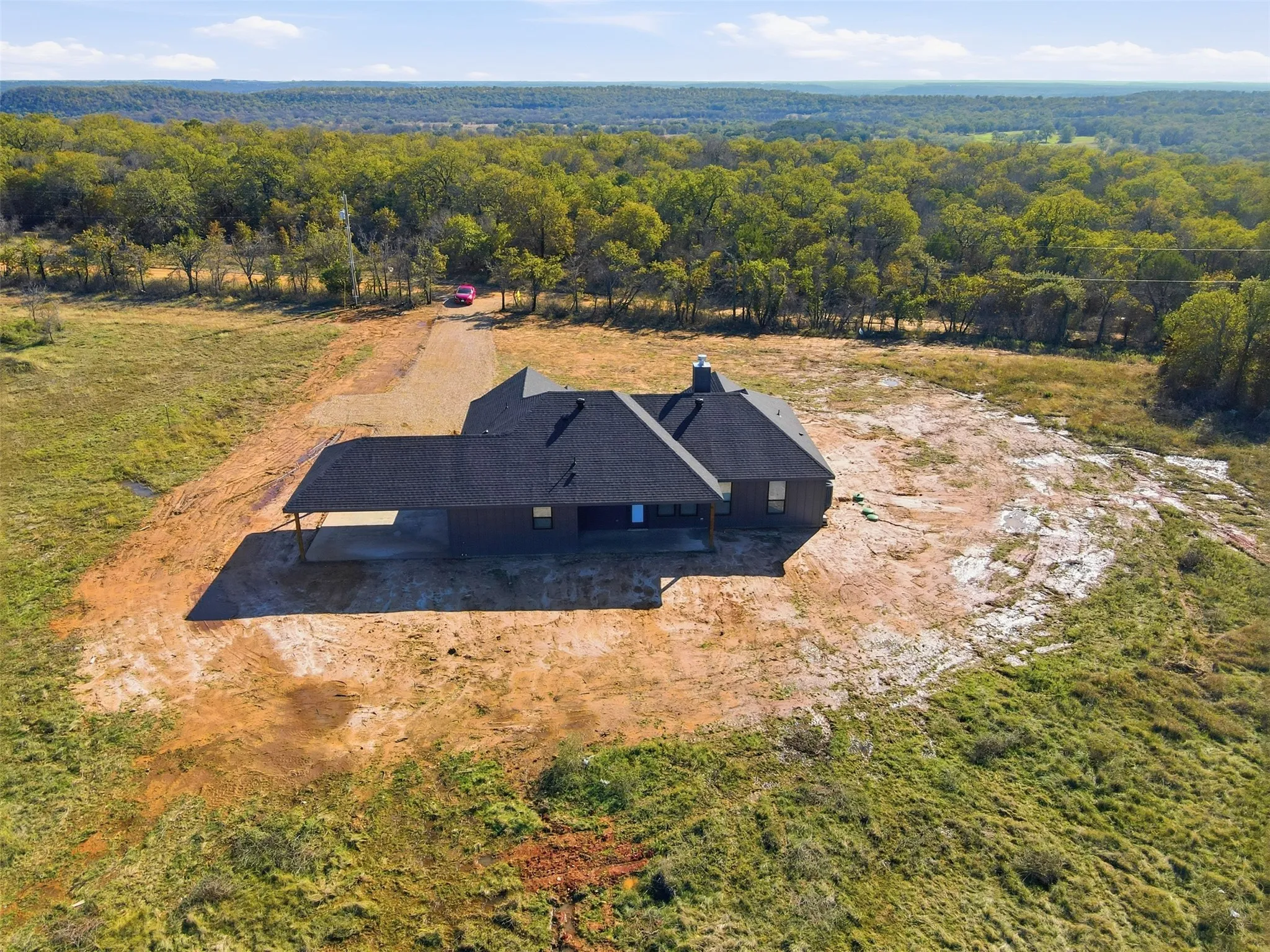Aerial view of property and surrounding area featuring a forest