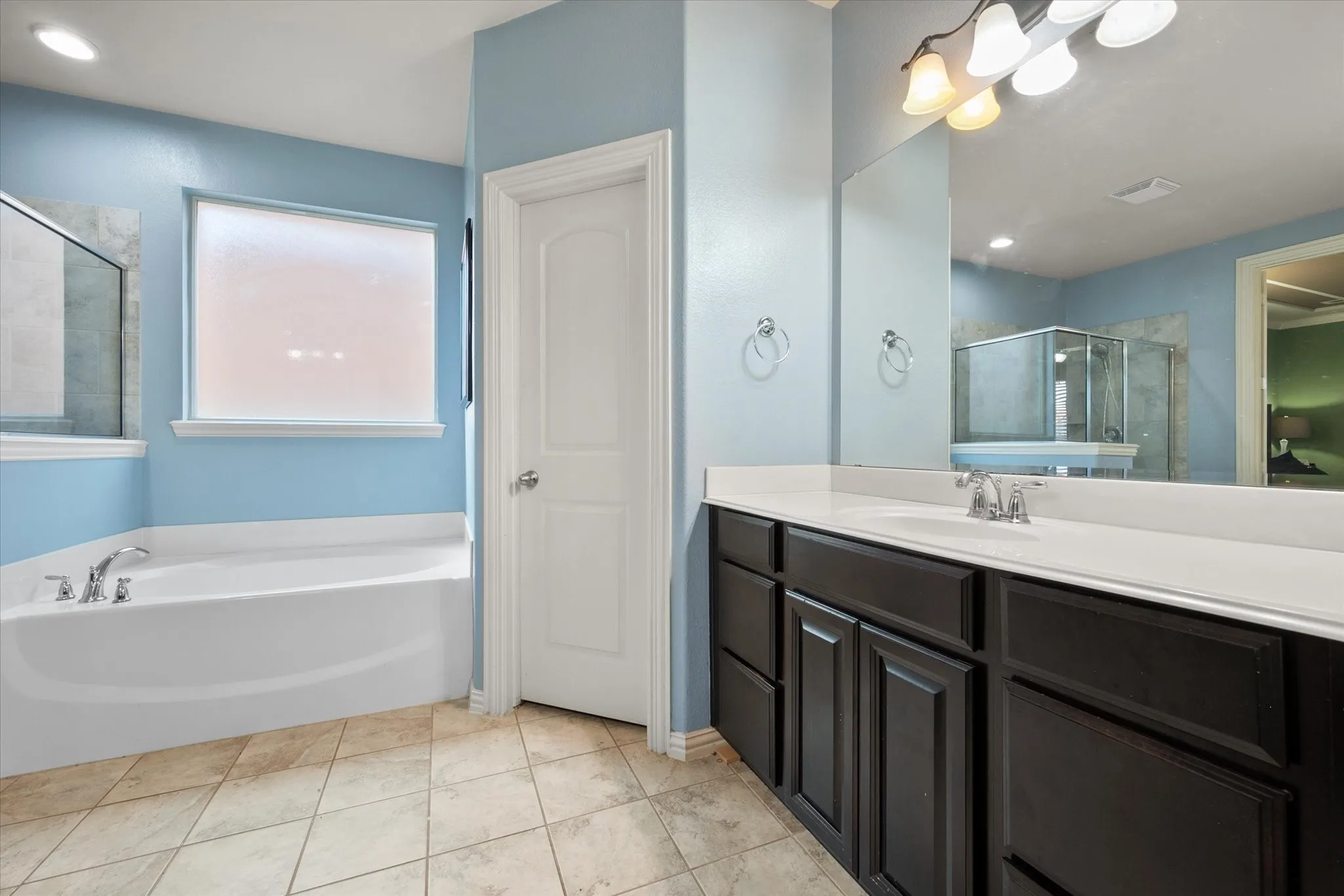 Primary ensuite bath with dual sinks, a soaker tub, and walk in shower