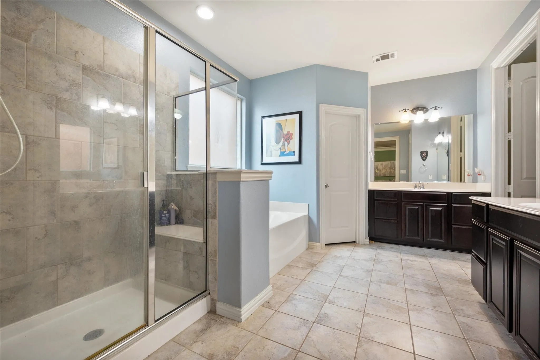Primary ensuite bath with dual sinks, a soaker tub, and walk in shower