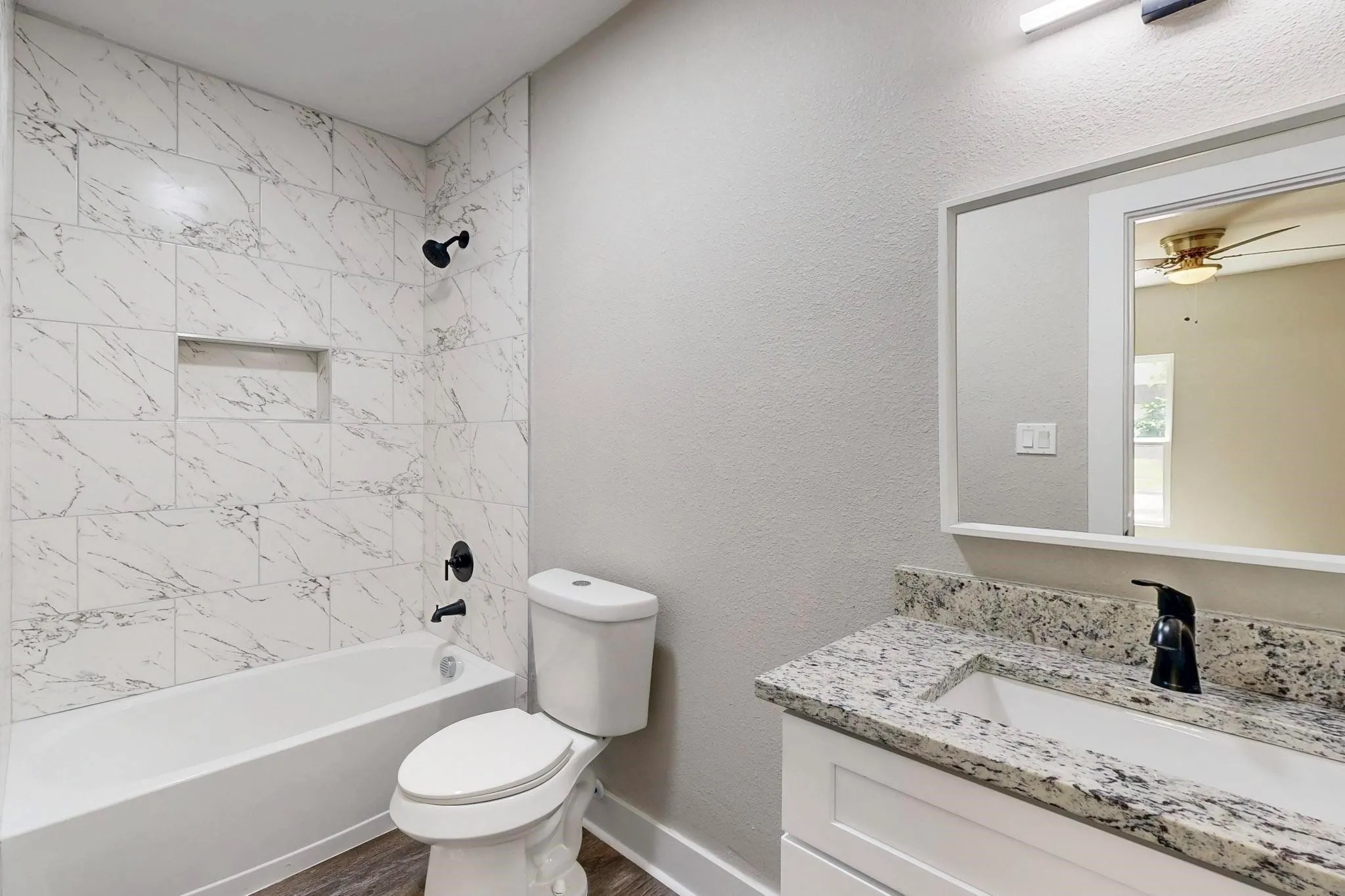 Full bath featuring vanity, bathtub / shower combination, a textured wall, a ceiling fan, and dark wood finished floors
