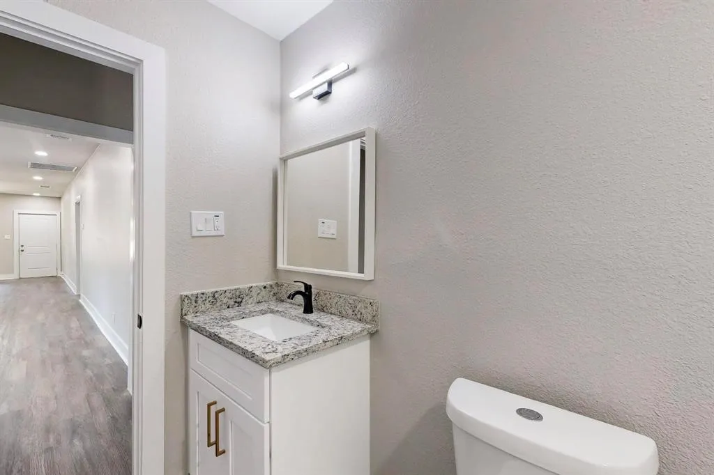 Bathroom with vanity, a textured wall, and wood finished floors
