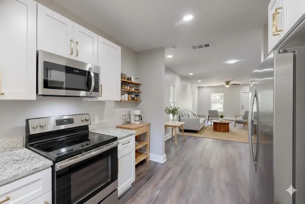 Kitchen with appliances with stainless steel finishes, open shelves, recessed lighting, light stone countertops, and white cabinets