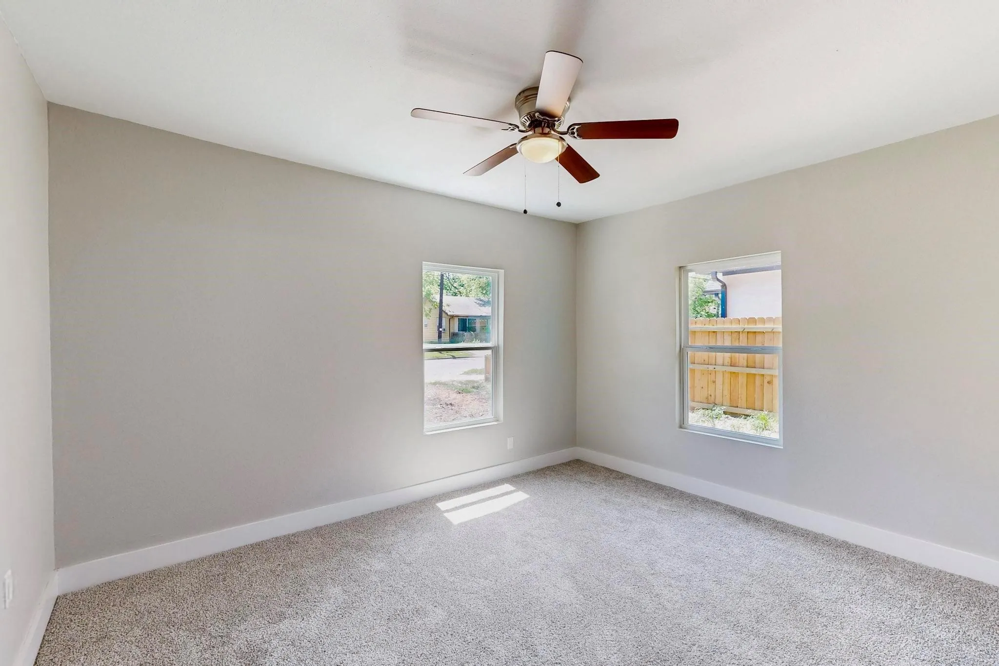 Empty room featuring carpet floors, plenty of natural light, and a ceiling fan