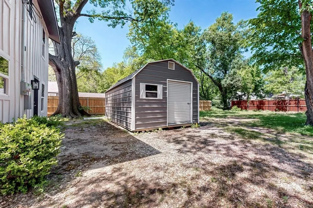 View of shed featuring a fenced backyard and view of scattered trees