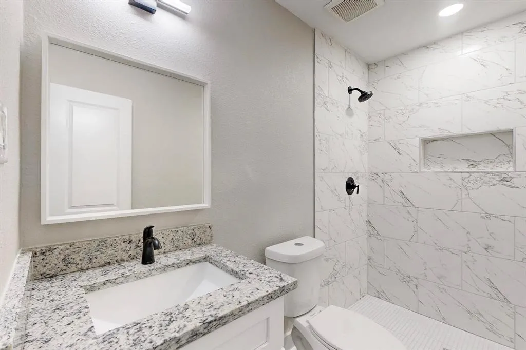 Bathroom featuring vanity, a shower stall, and a textured wall