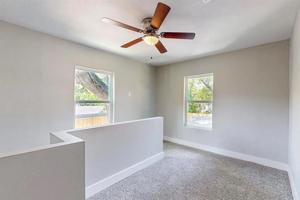 Carpeted spare room with plenty of natural light and a ceiling fan