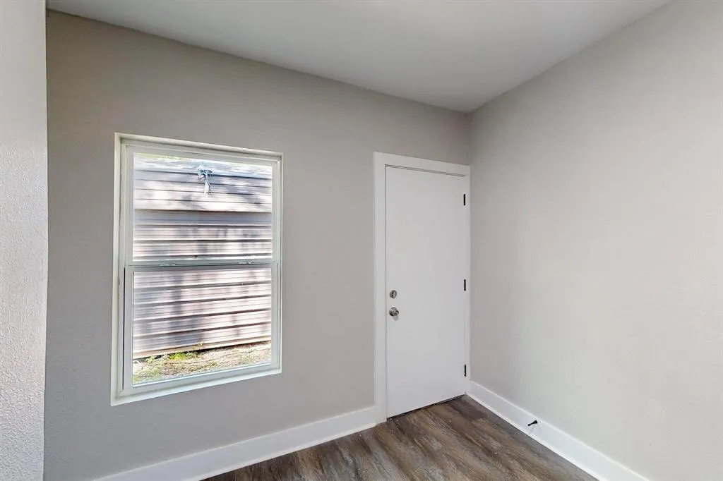 Unfurnished room featuring baseboards and dark wood-style flooring