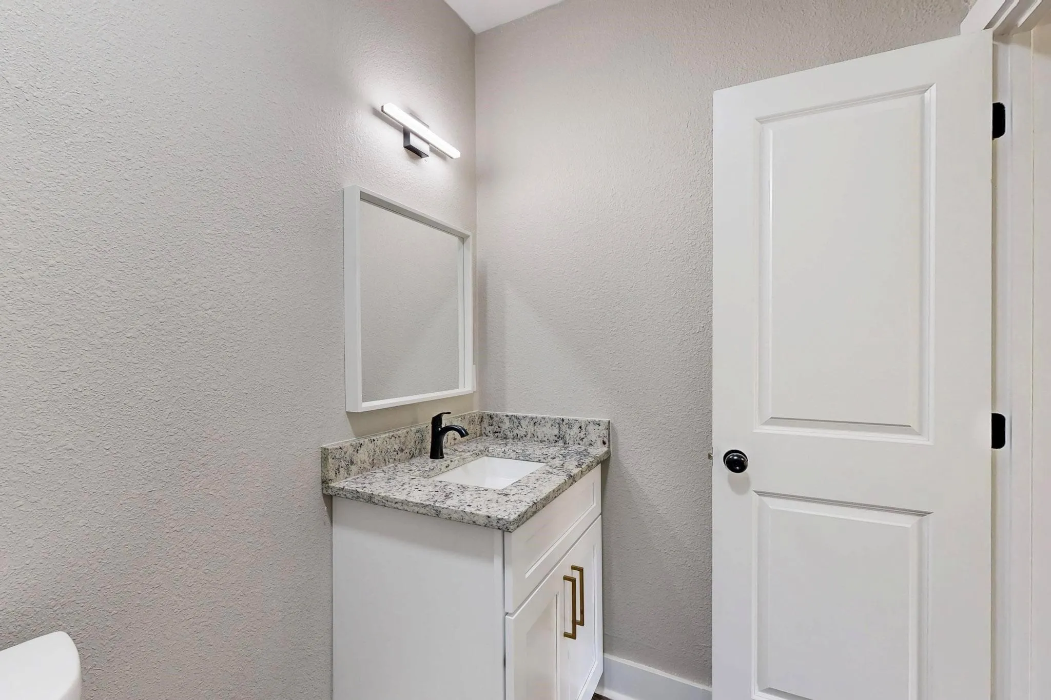 Bathroom featuring a textured wall and vanity