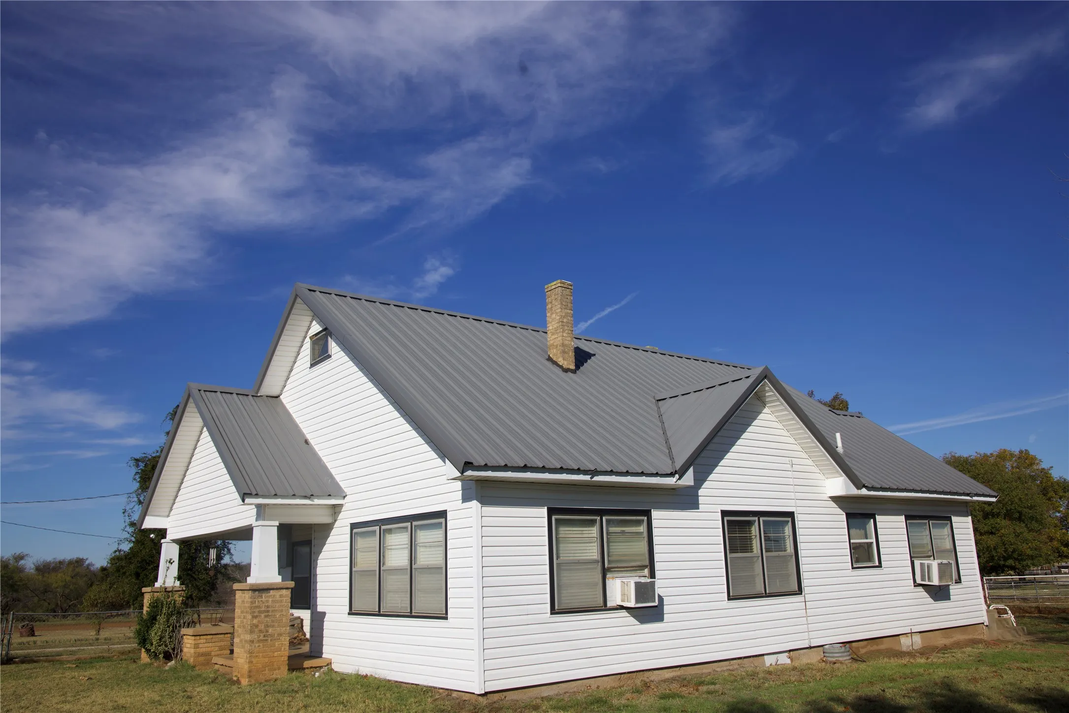 View of home's exterior featuring a metal roof, cooling unit, and a chimney