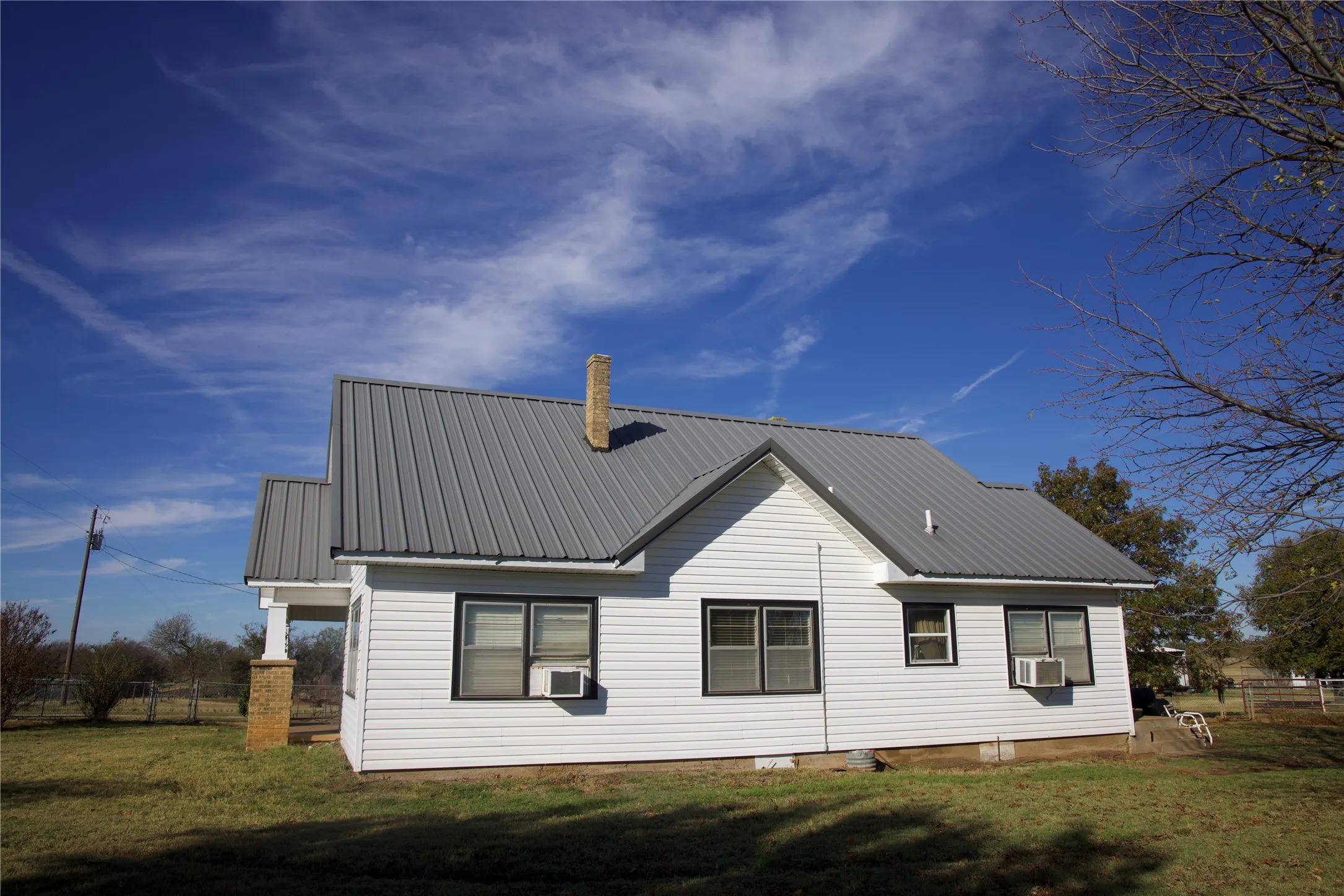Back of house featuring a metal roof, cooling unit, and a chimney